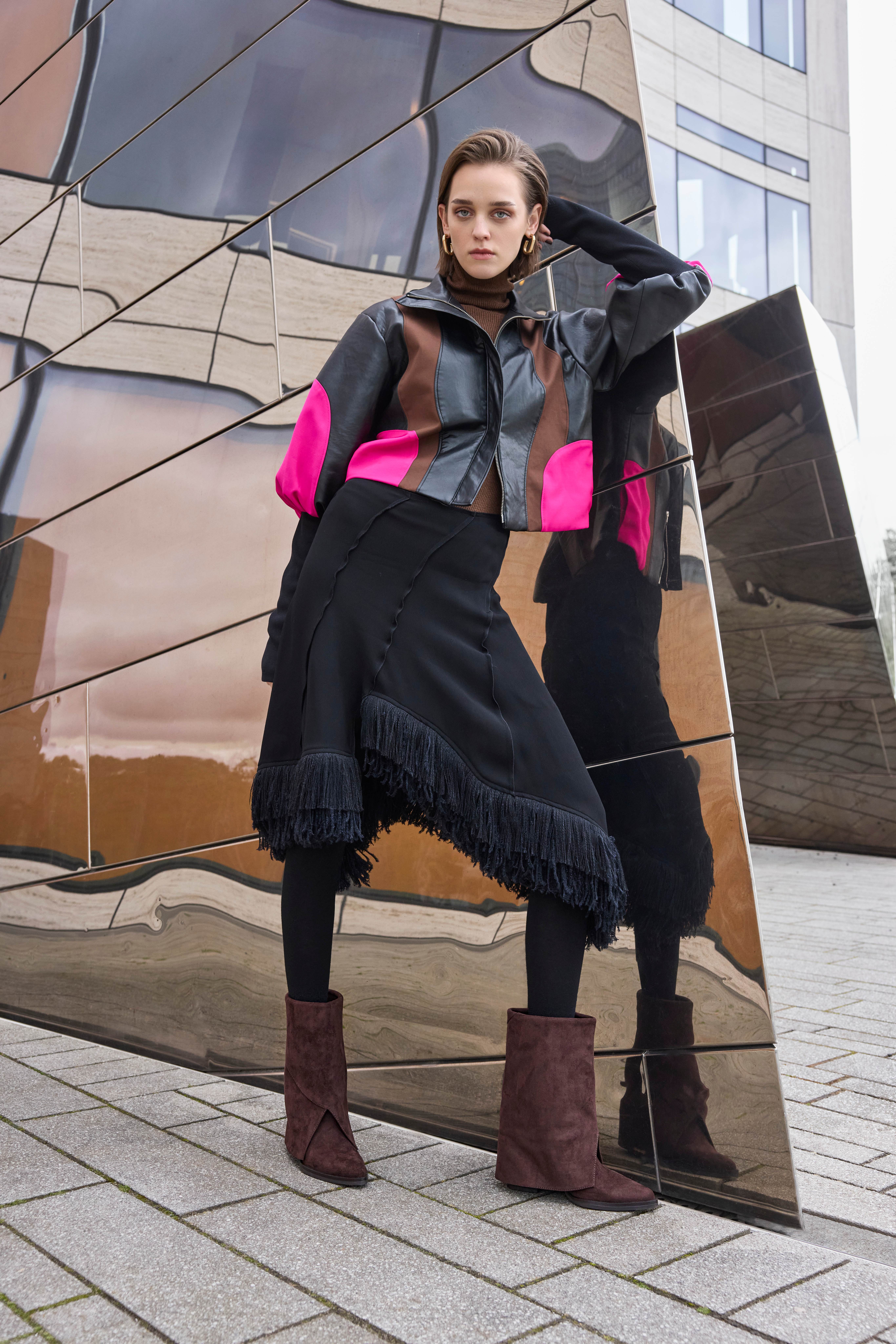 Eine Frau trägt ein schwarzes Outfit mit pinken Akzenten und braune Shark Boots