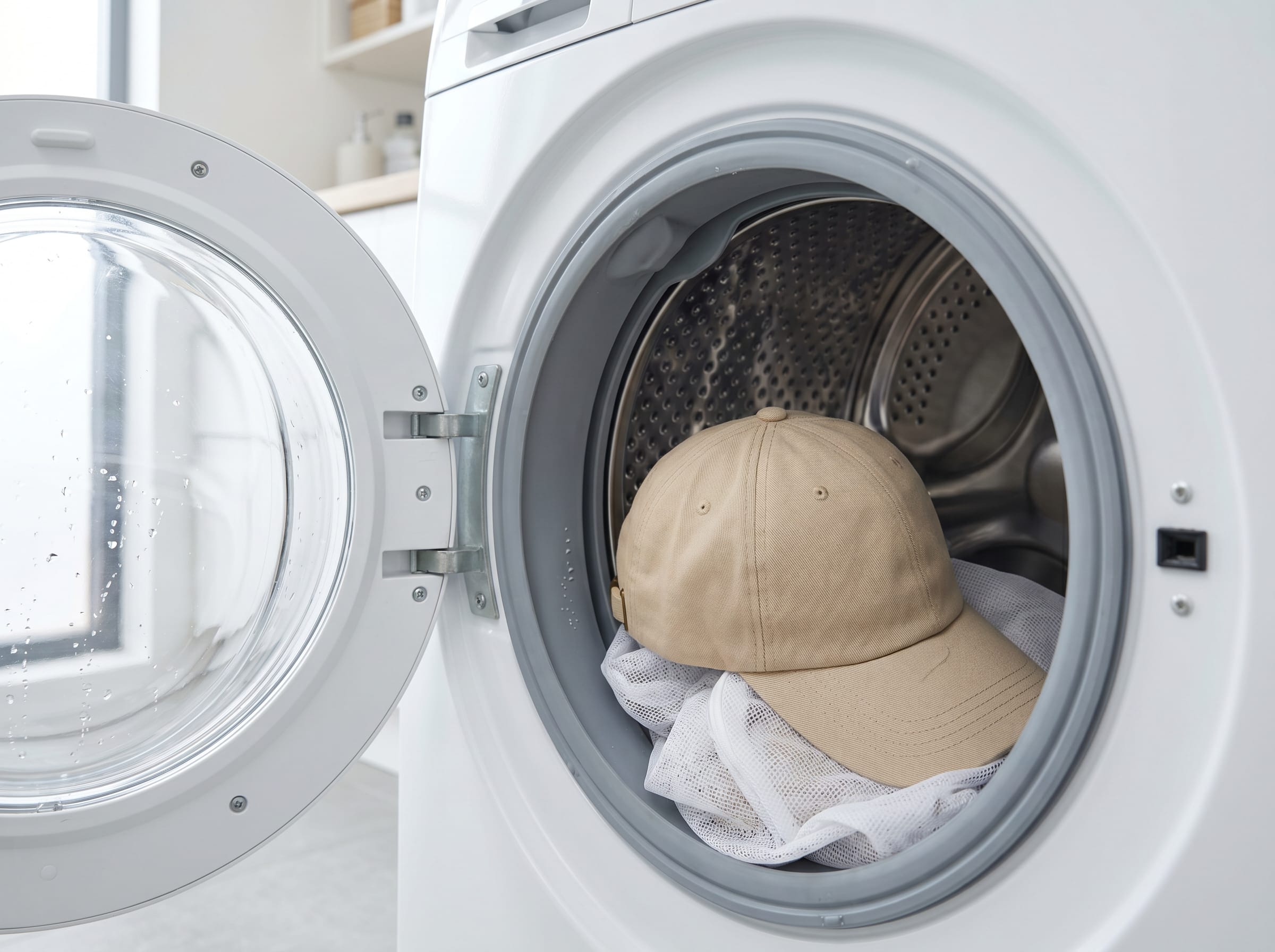 Baseballcap liegt in einer Waschmaschine mit geöffneter Klappe
