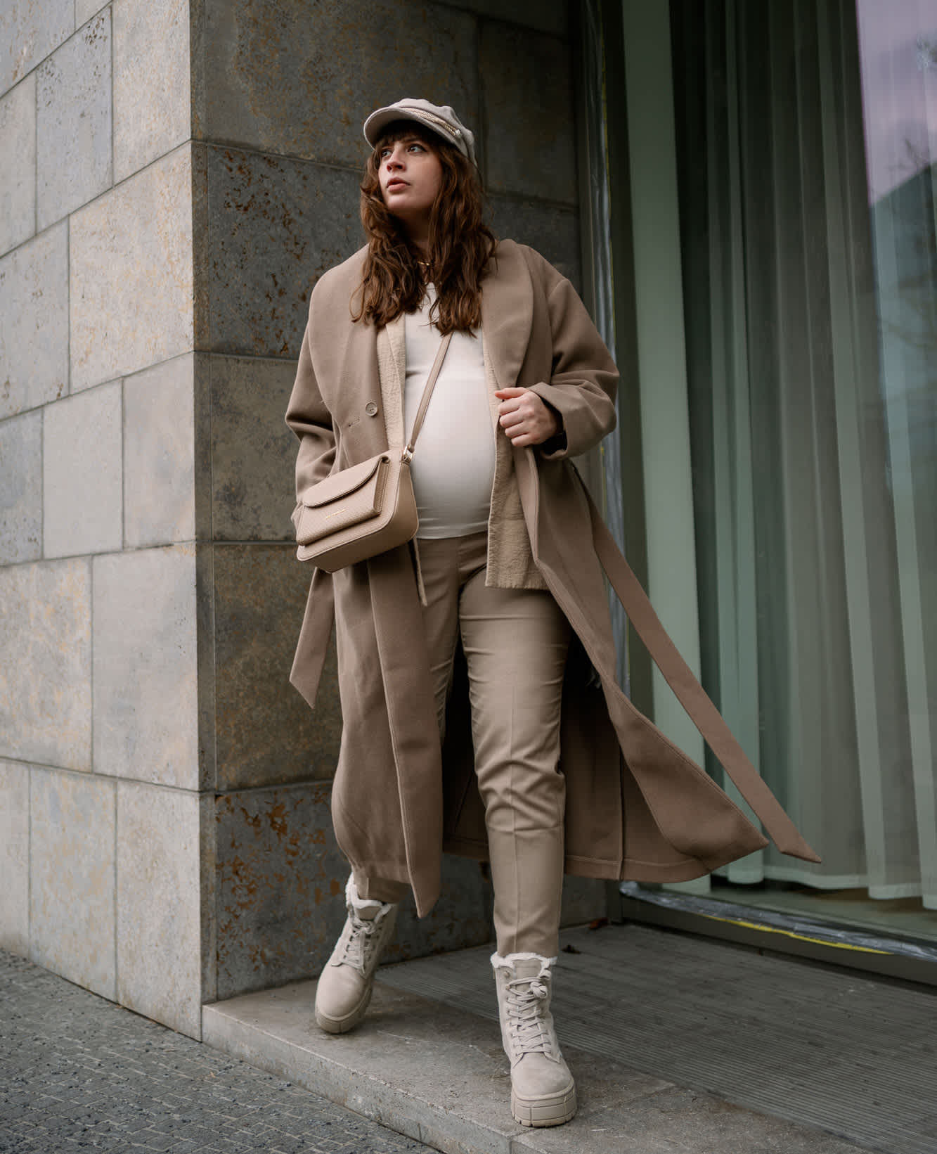 Frau in Business Core-Mantel blickt zur Seite, trägt Tasche über Schulter