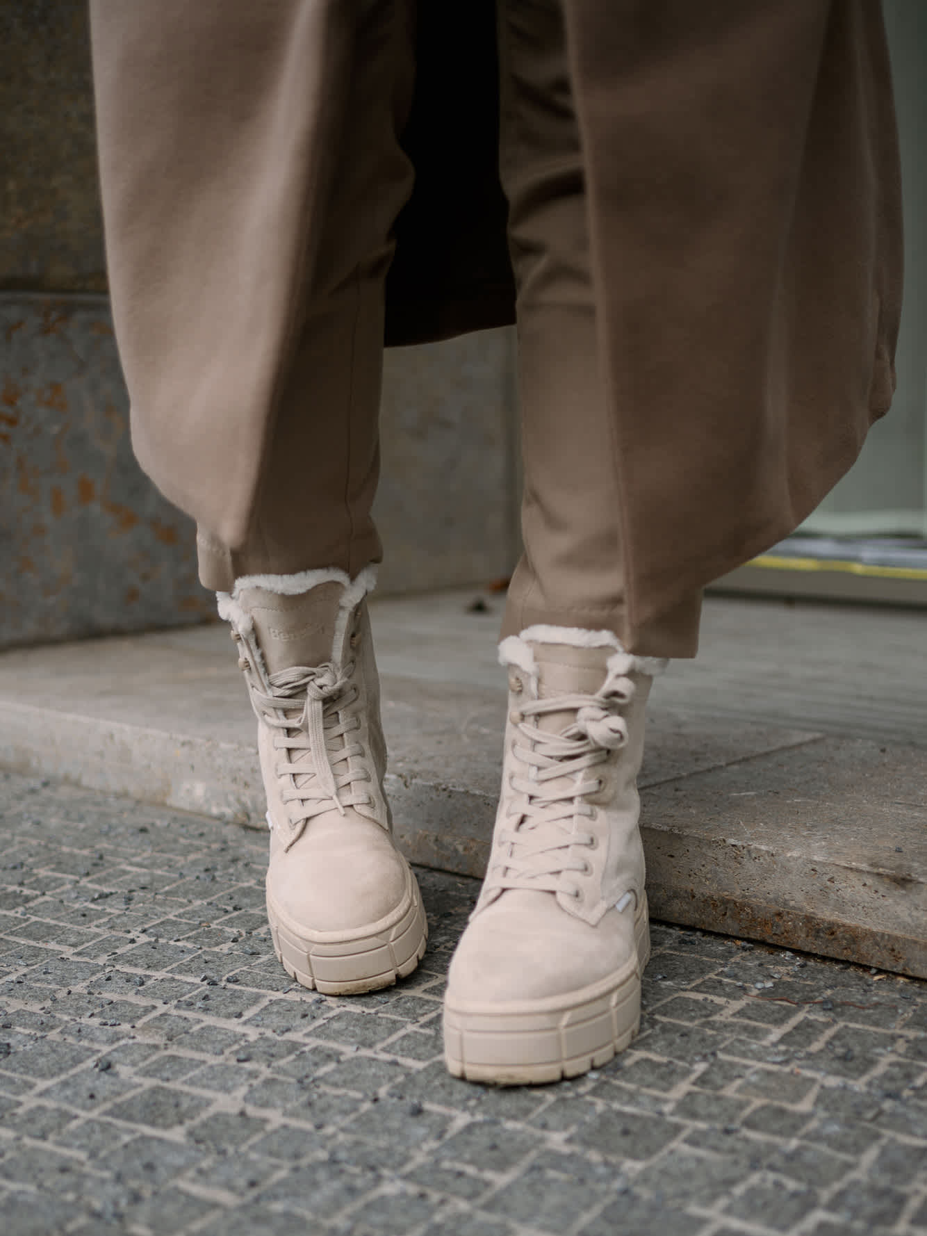 Nahaufnahme beiger Boots auf Stein-Untergrund