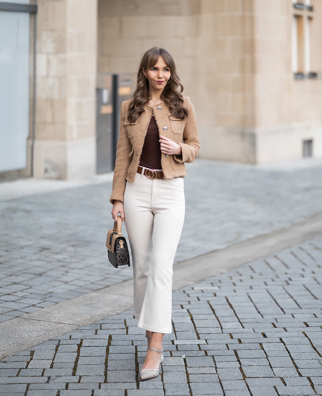 Frau in braunem Blazer und weißer Hose samt Handtasche als Outfit für ein Date