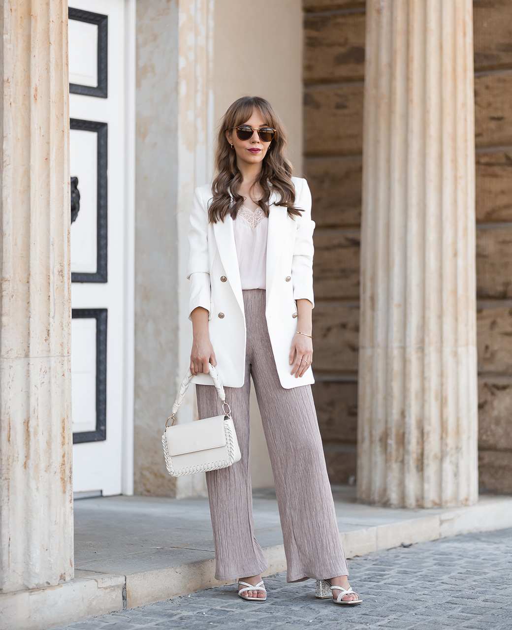 Frau in entspanntem Glamour-Outfit, weißer Look abgerundet durch glitzernde Schuhe