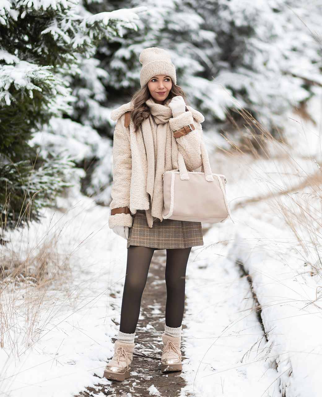 Frau in Teddyfell-Outfit, mit flauschiger Handtasche, vor winterlicher Kulisse