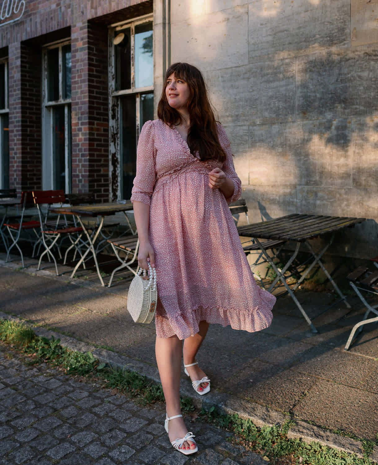 Frau in pastellfarbenem Kleid, mit weißen Pumps und passender Handtasche