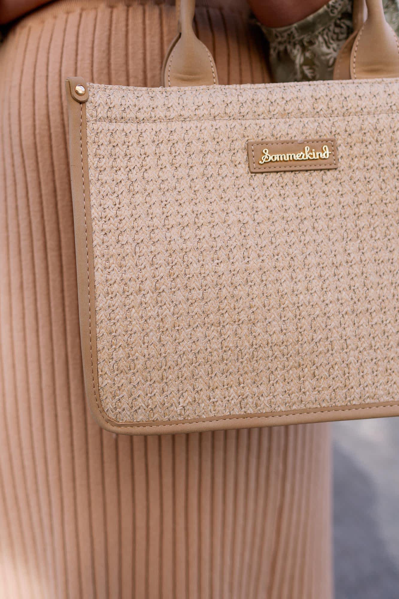 Frau trägt beige Handtasche mit goldener Aufschrift "Sommerkind" am Arm