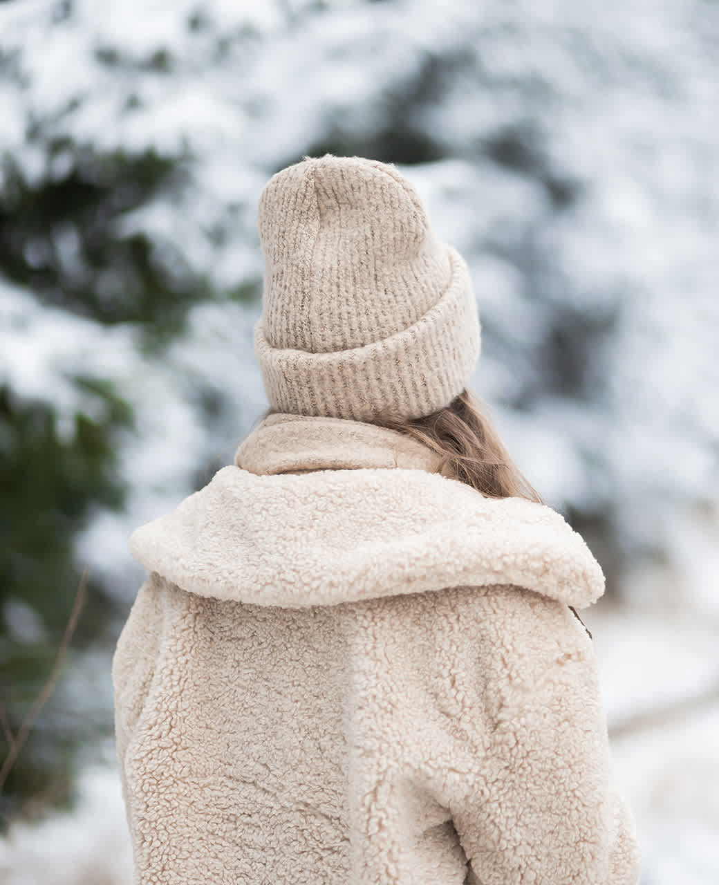 Rückansicht einer Person mit beigefarbenem Outfit aus Teddystoff, mit passender Jacke und Mütze