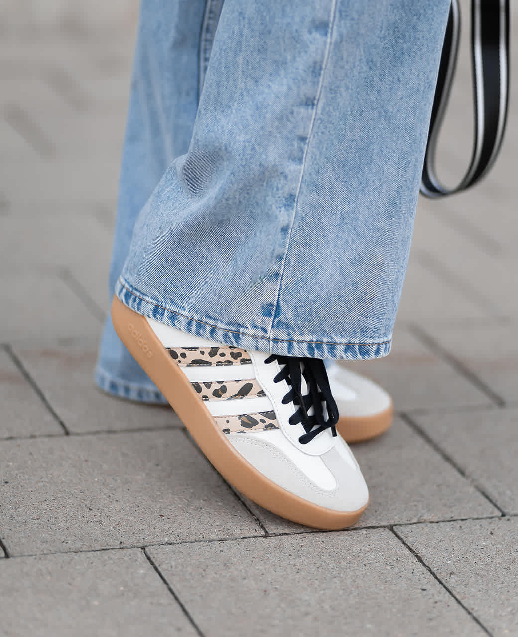 Frau trägt weiße Retro-Sneaker zu blauen Wide Leg Jeans