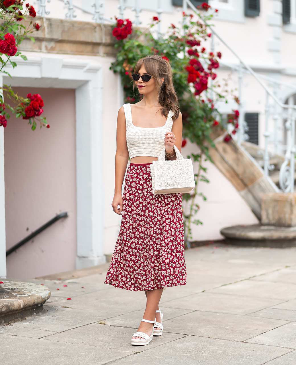 Frau in weißem Top und rot-weiß gepunktetem Rock, trägt weiße Boho Bag am Arm