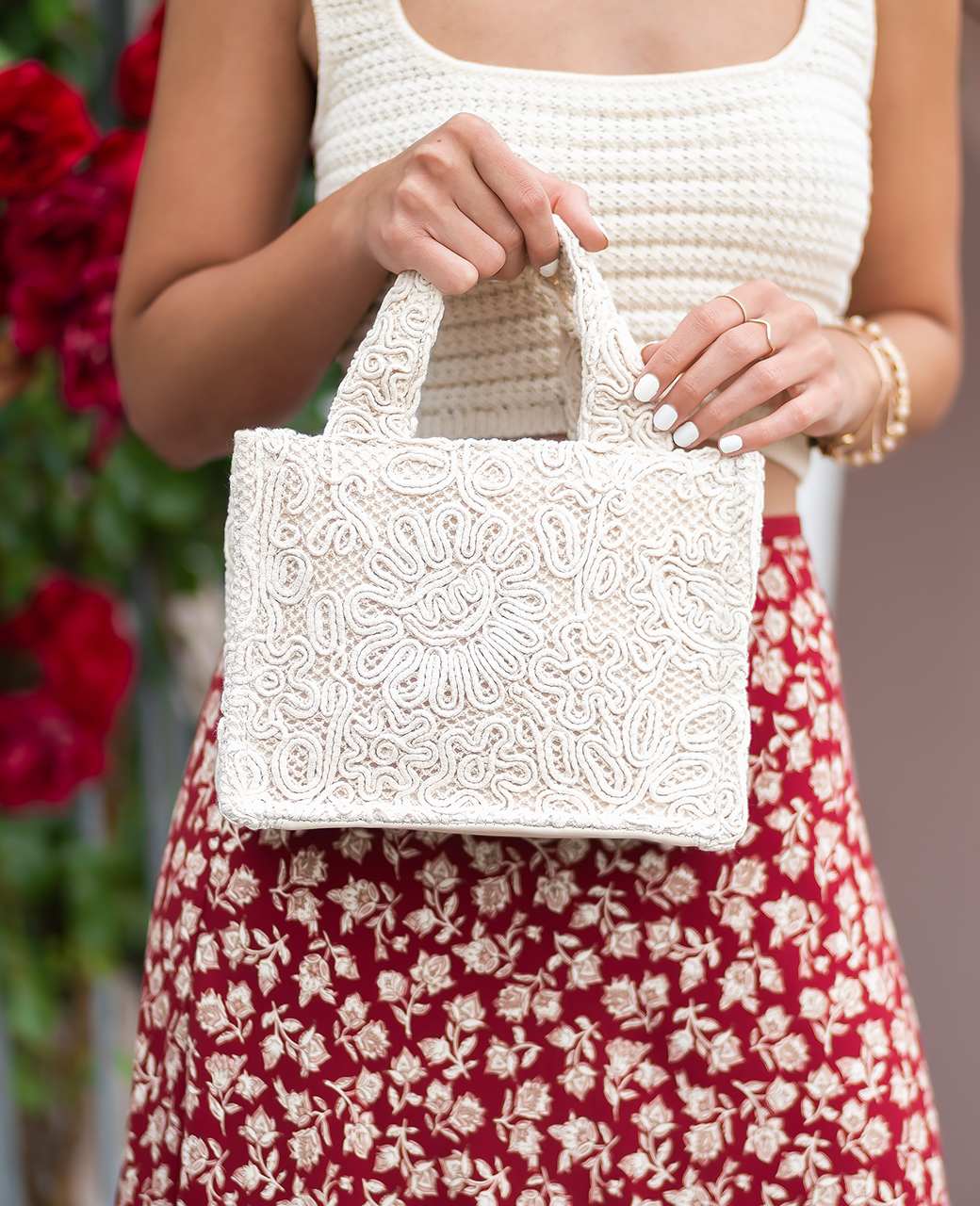 Frau hält weiße Boho-Tasche an der Schlaufe