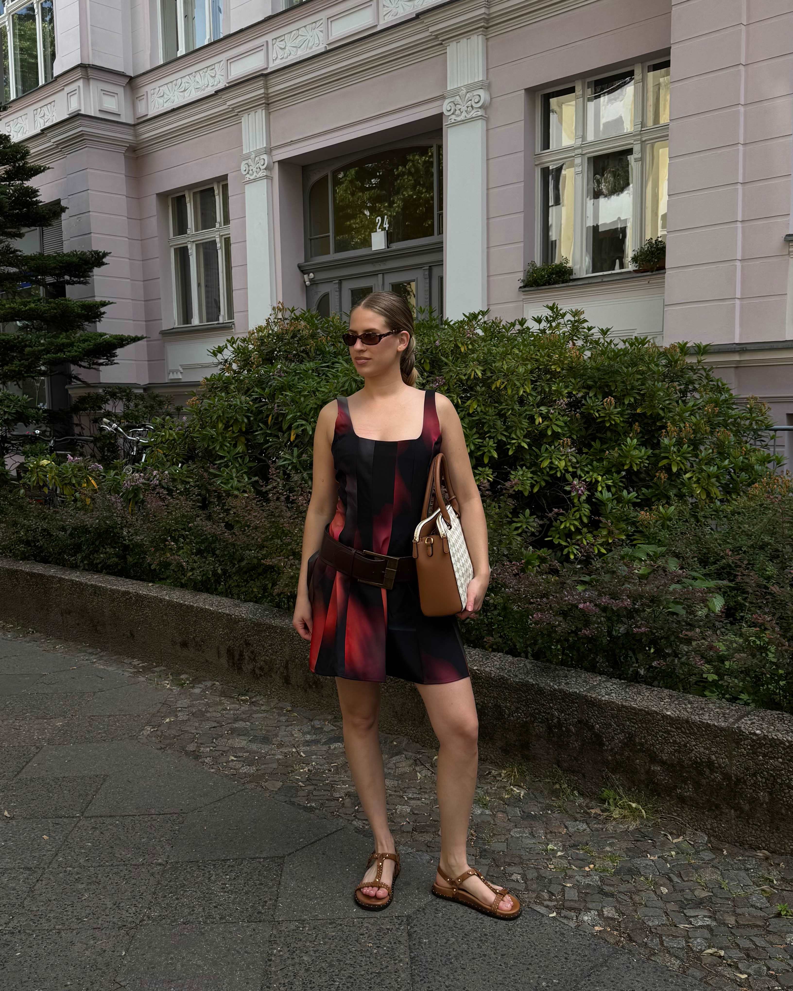 Frau in rotem Kleid und offenen Schuhen mit Riemchen, kombiniert mit einer Tasche