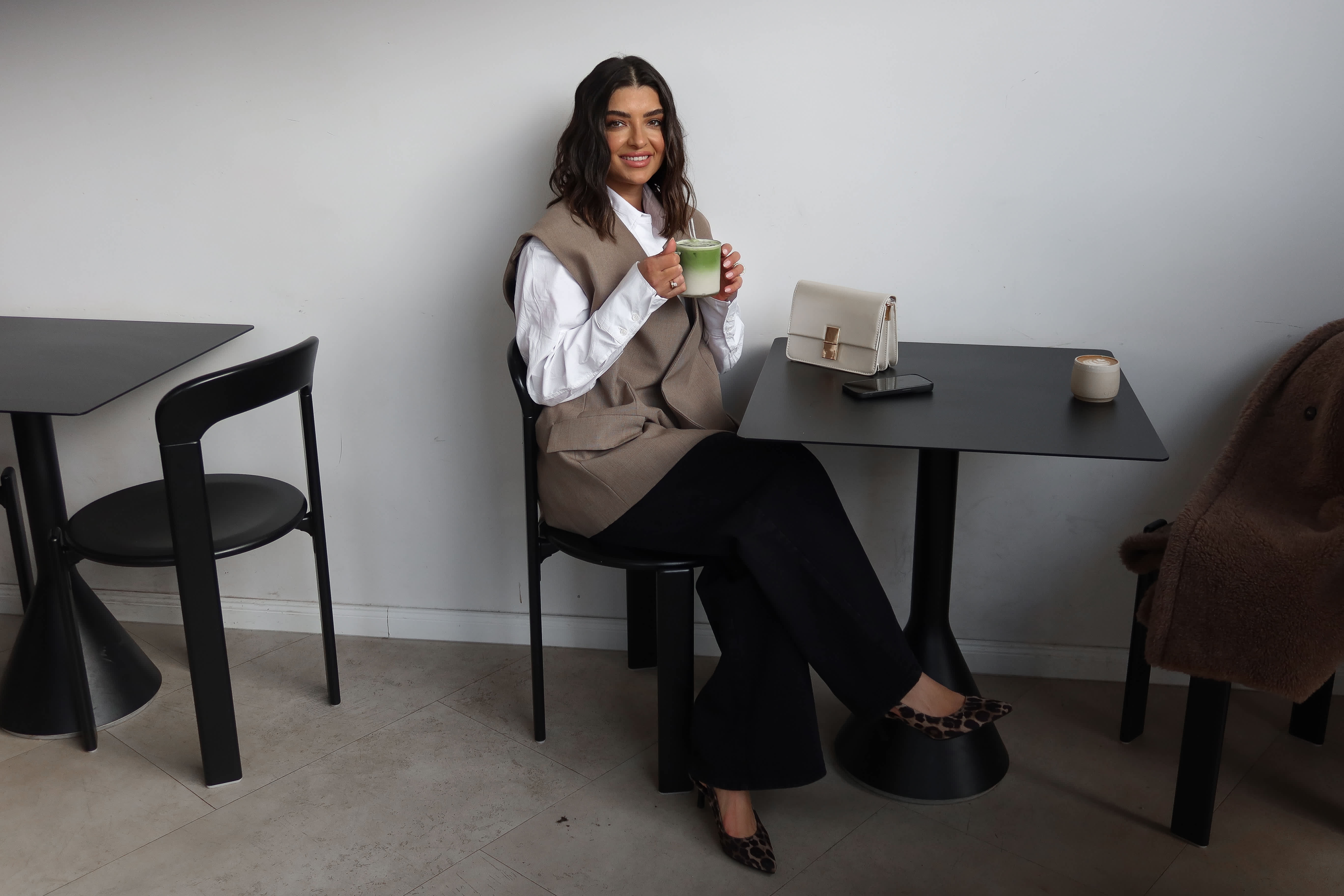 Frau sitzt entspannt mit einer Kaffeetasse an einem Tisch