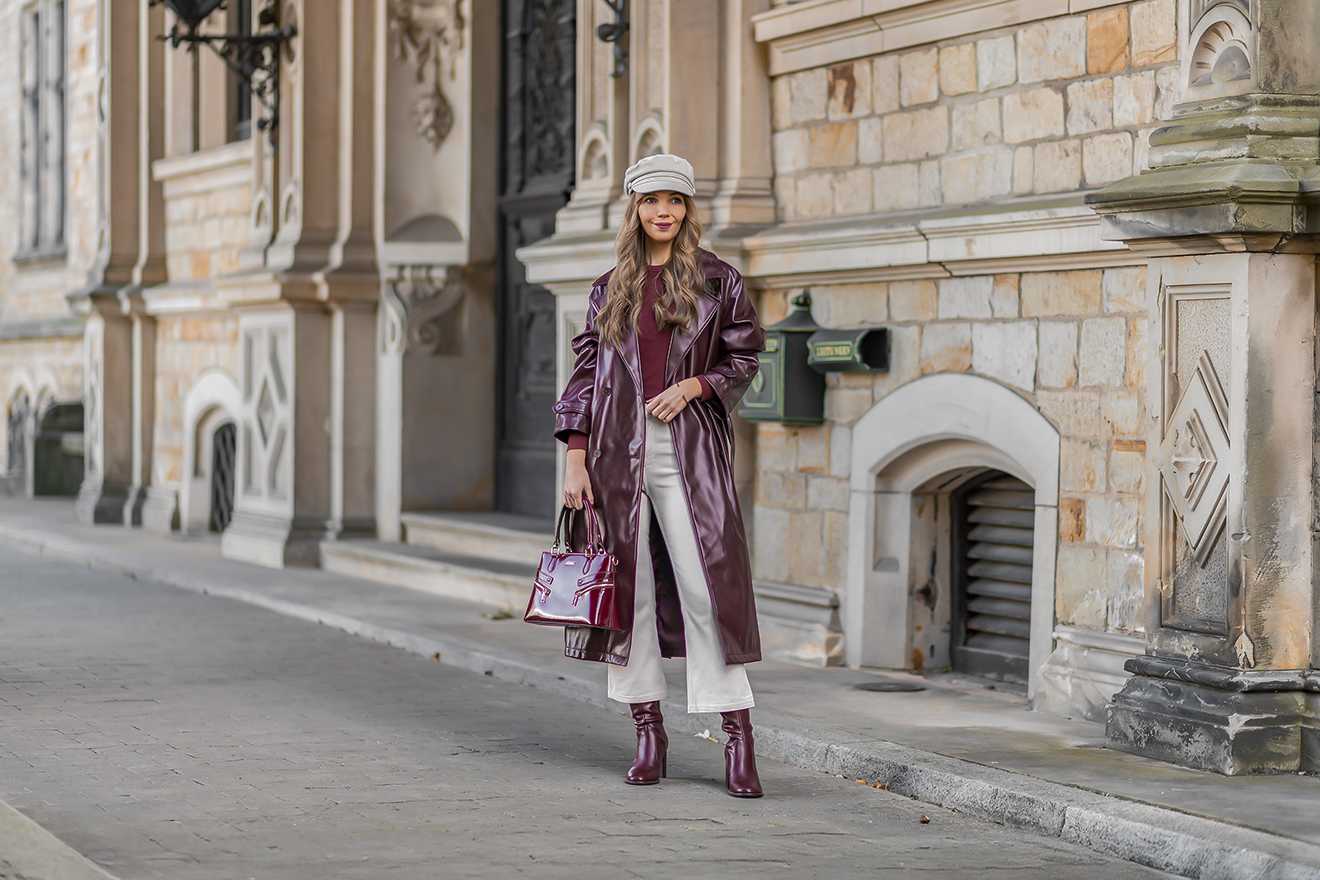 Frau in violett-glänzendem Mantel, kombiniert mit passender Handtasche und Stiefeletten