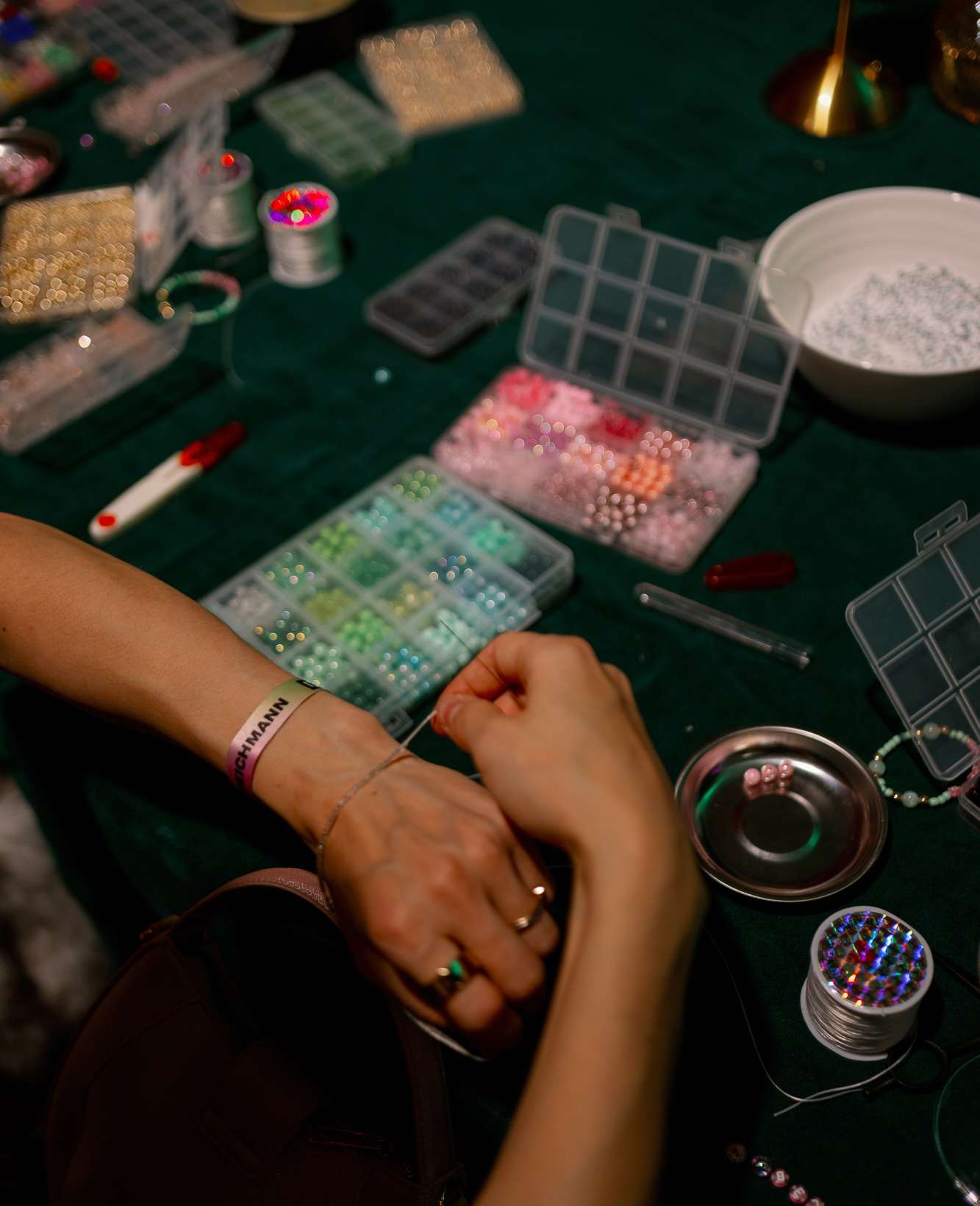 Person probiert Bracelets an einer Bastelstation an