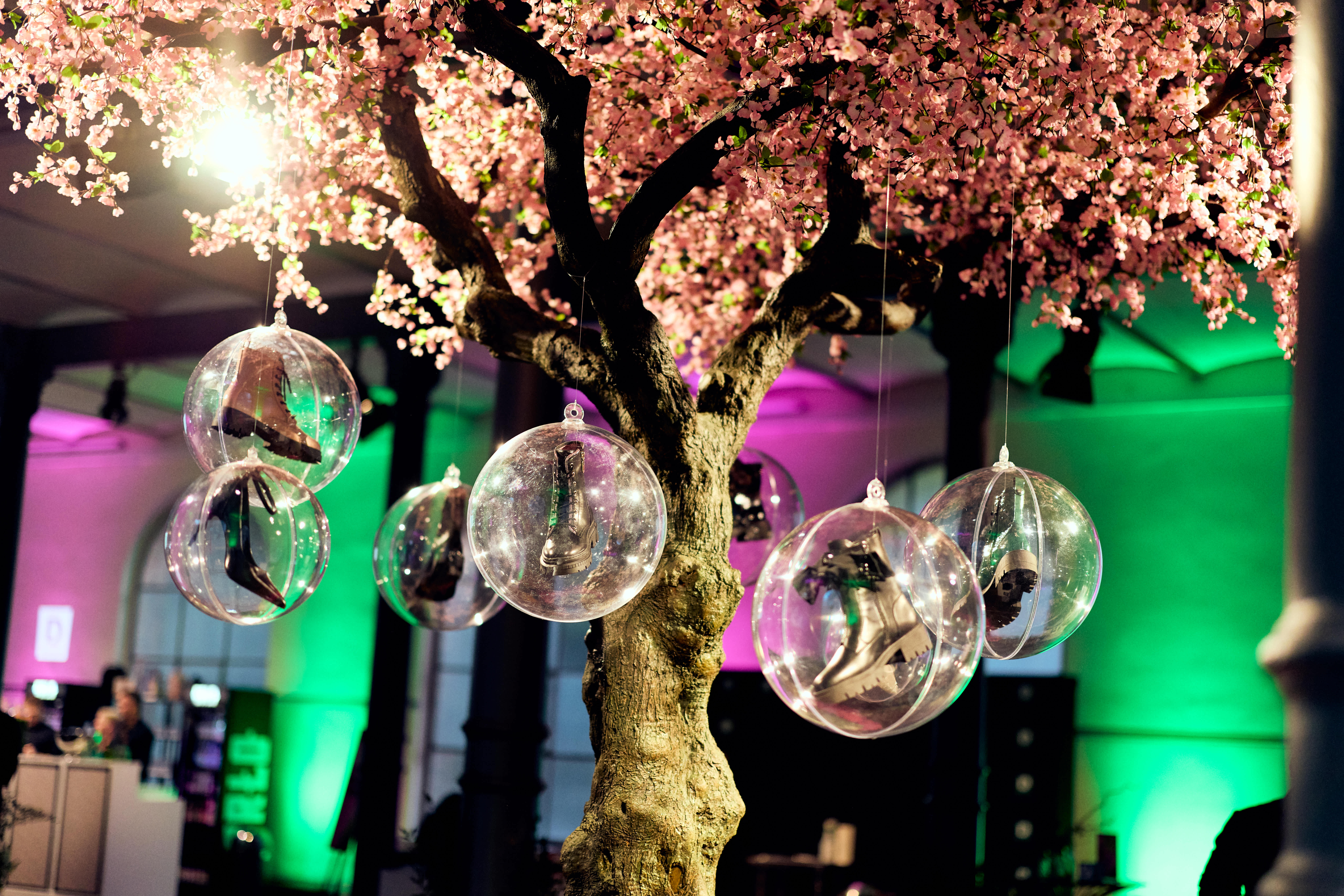 Glaskugeln mit Miniatur-Stiefeln hängen an einem Baum mit rosa Blüten