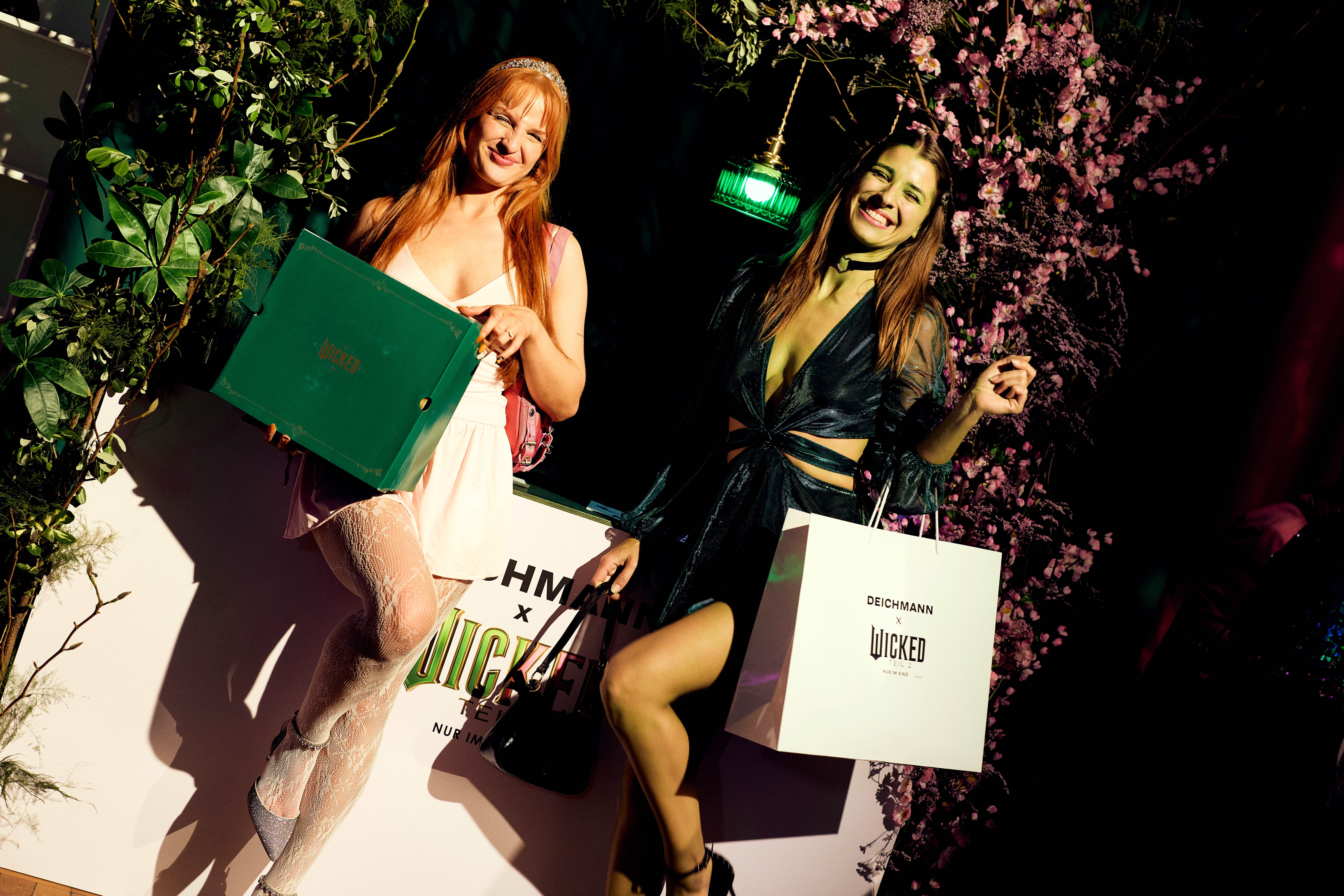 Zwei Frauen in Wicked-Outfits, gekleidet als Glinda und Elphaba, posieren auf Deichmann x Wicked-Event