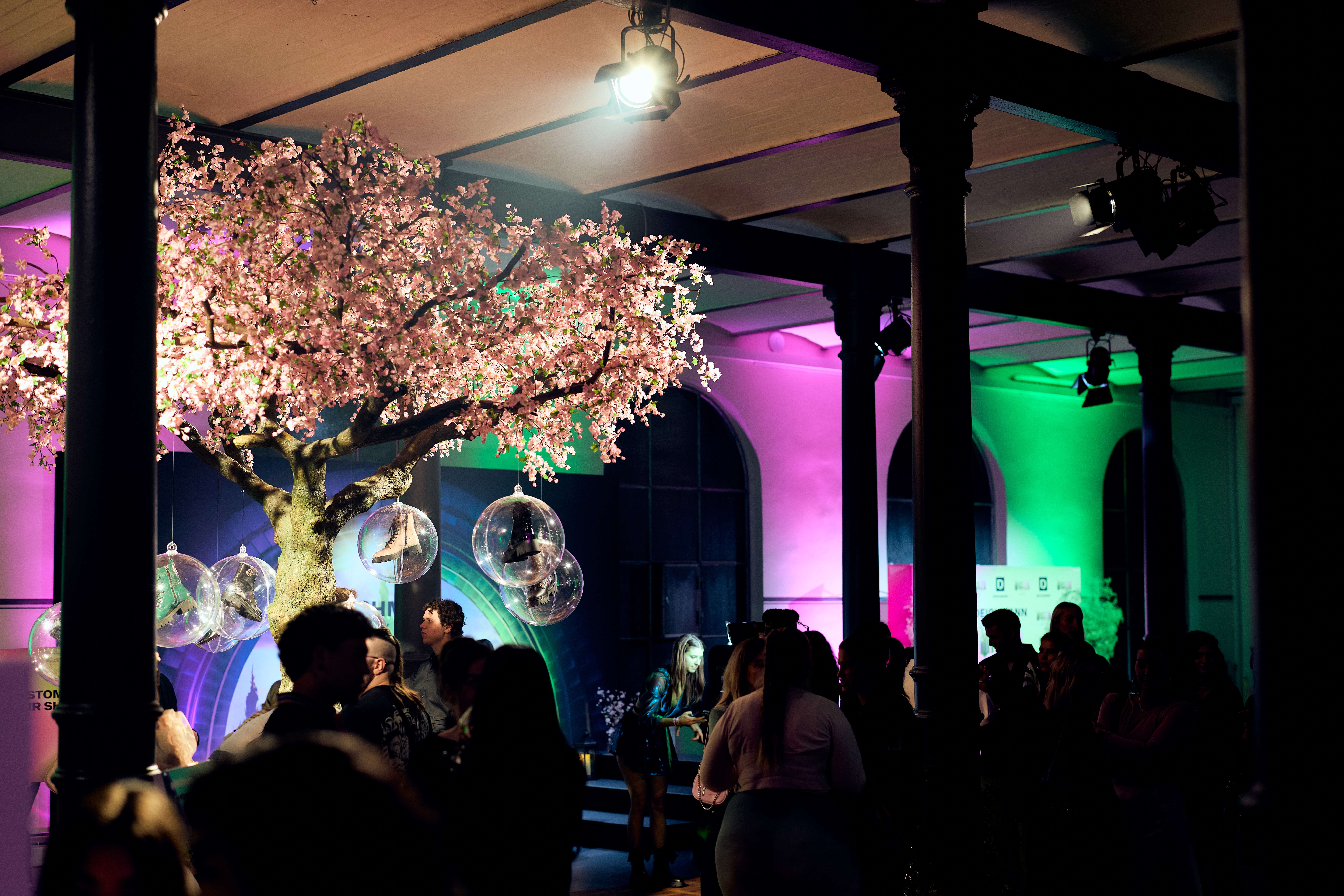 Eine Gruppe Besucher rund um den Kirschbaum beim Deichmann x Wicked-Event