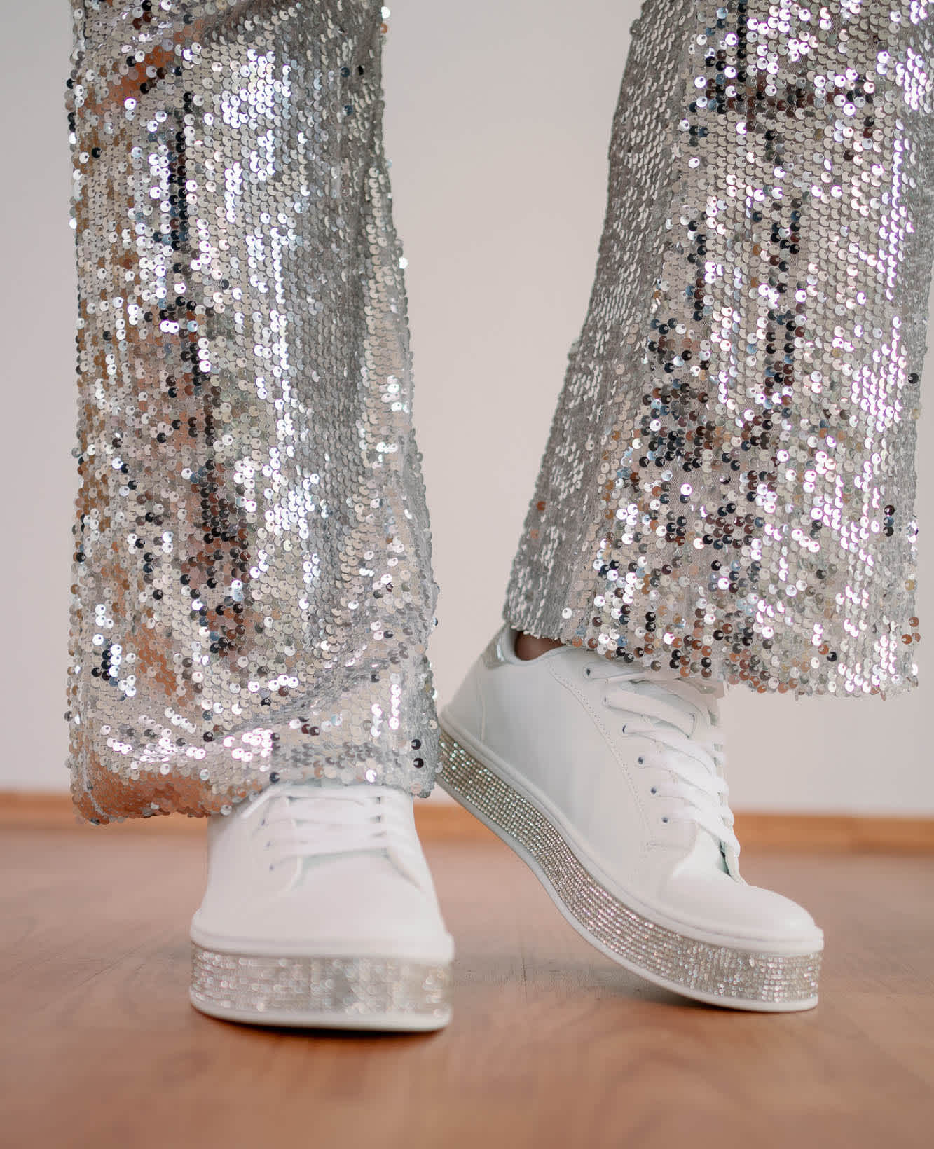 Close-Up einer Person mit weißen Sneakern + Pailetten-Hose