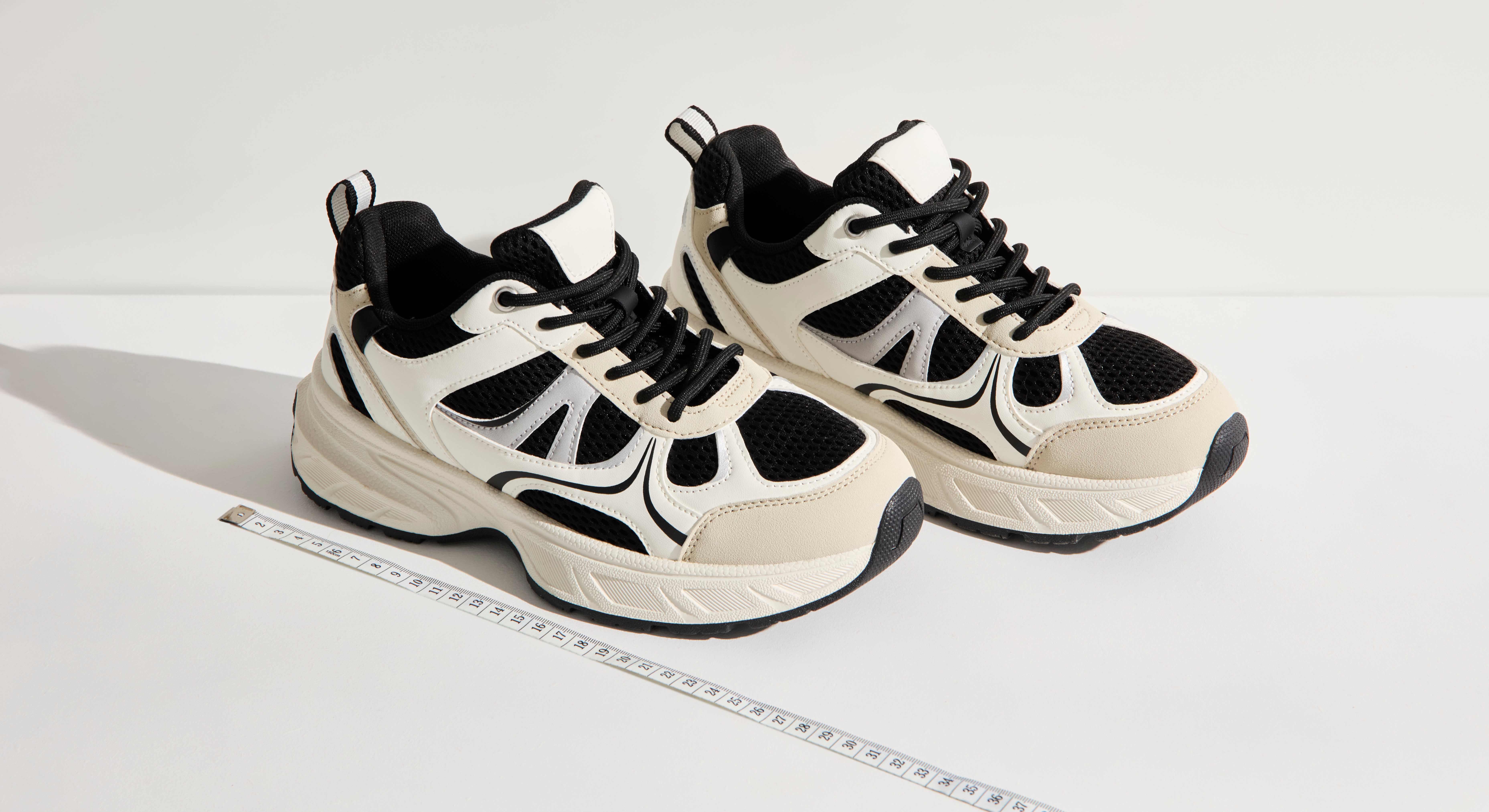 Sneaker-Schuhe stehen neben Maßband zum Messen der Schuhgröße