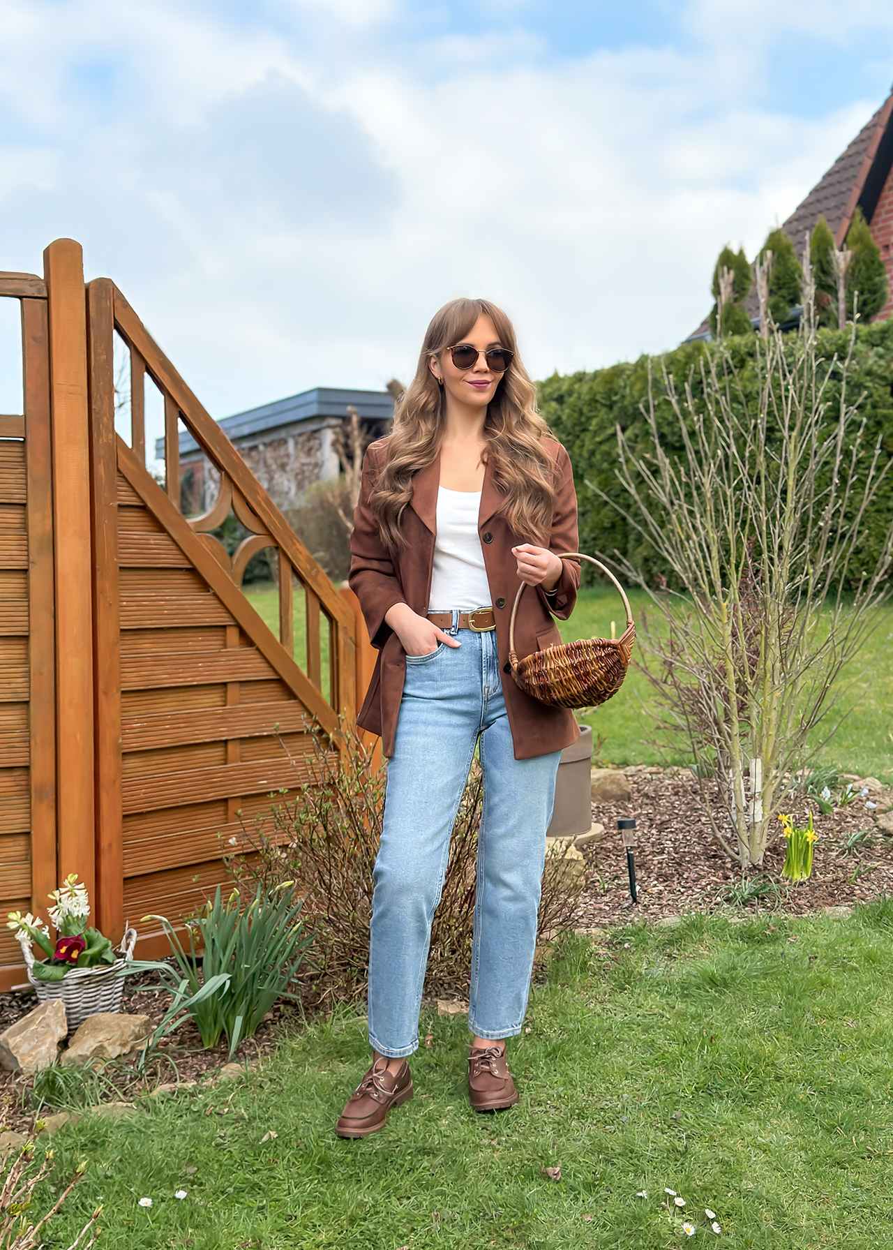 Junge Frau mit Sonnenbrille, posiert mit Holzfäller-Hemd und Jeanshose auf Wiese