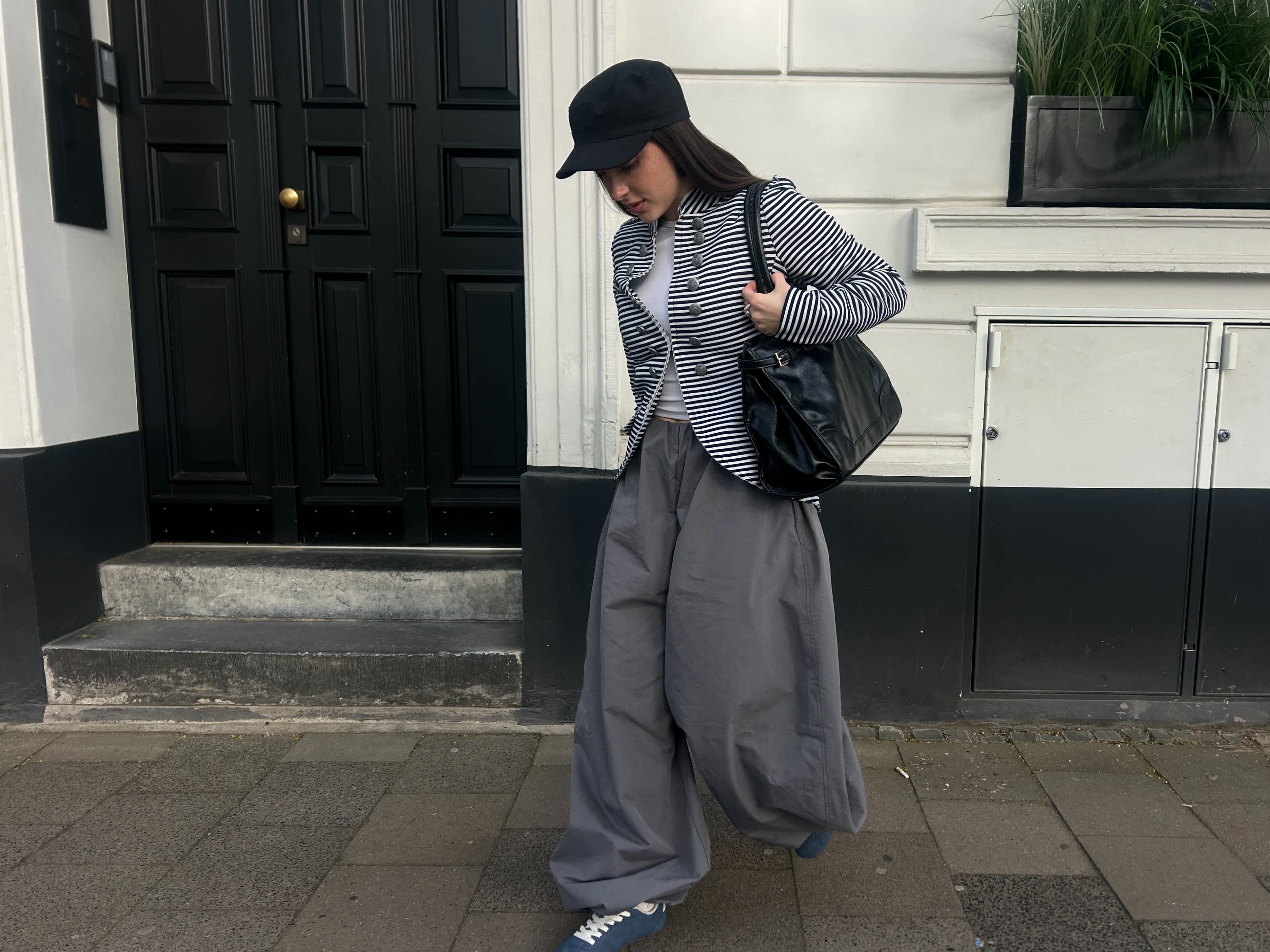 Frau in grau-schwarzem Outfit schaut hinunter auf ihre Sneaker-Schuhe