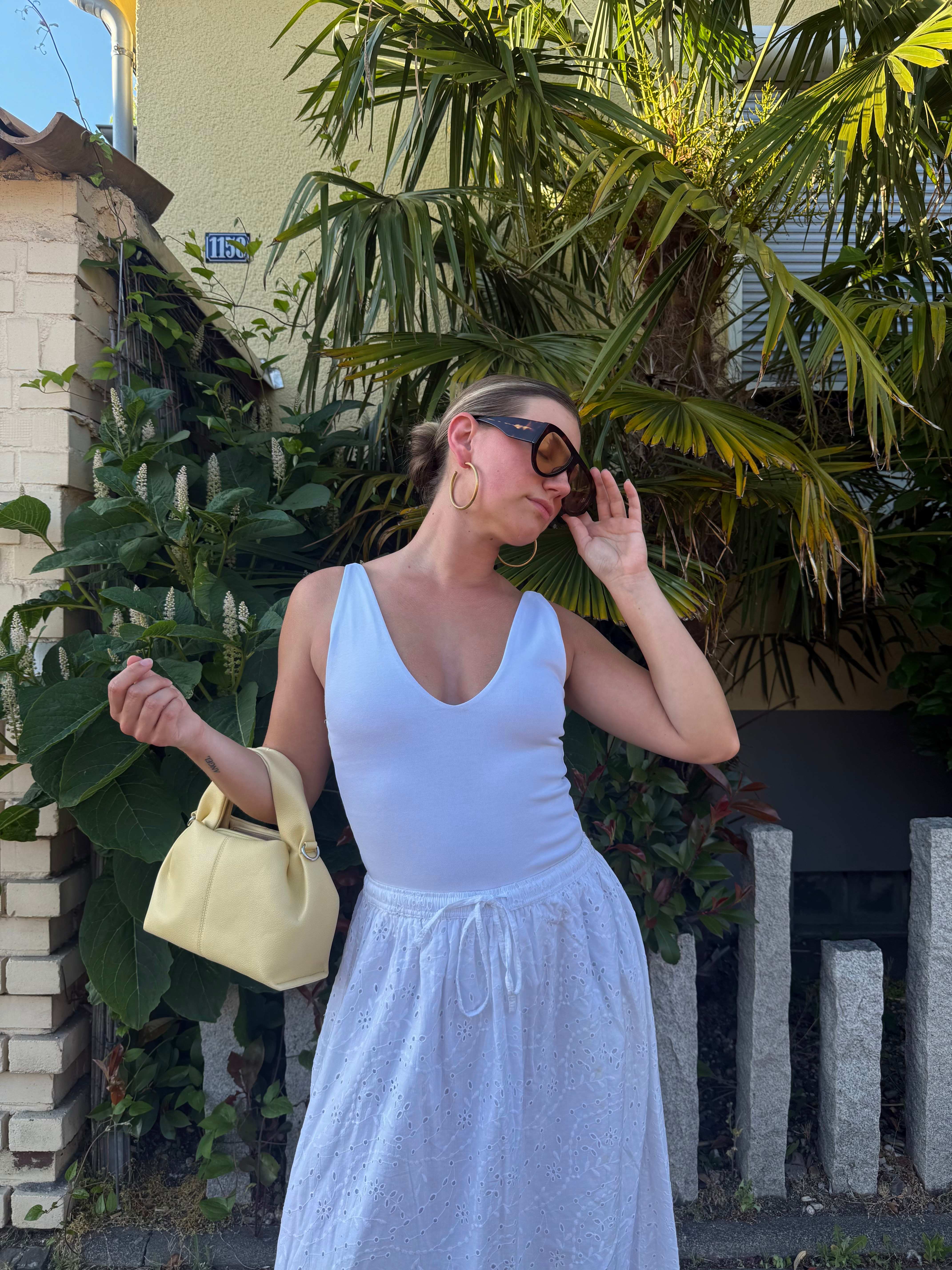 Frau zeigt sommerliche Accessoires zu ihrem Outfit mit Kork Wedges