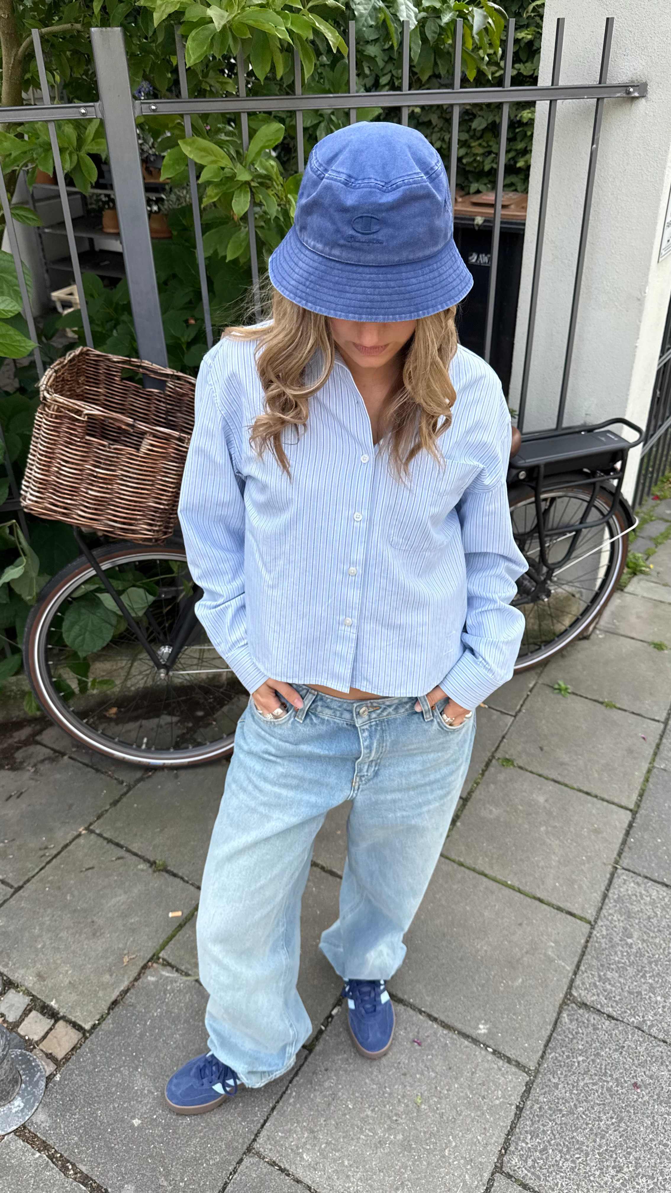 Frau zeigt ihr Outfit mit Bucket Hat