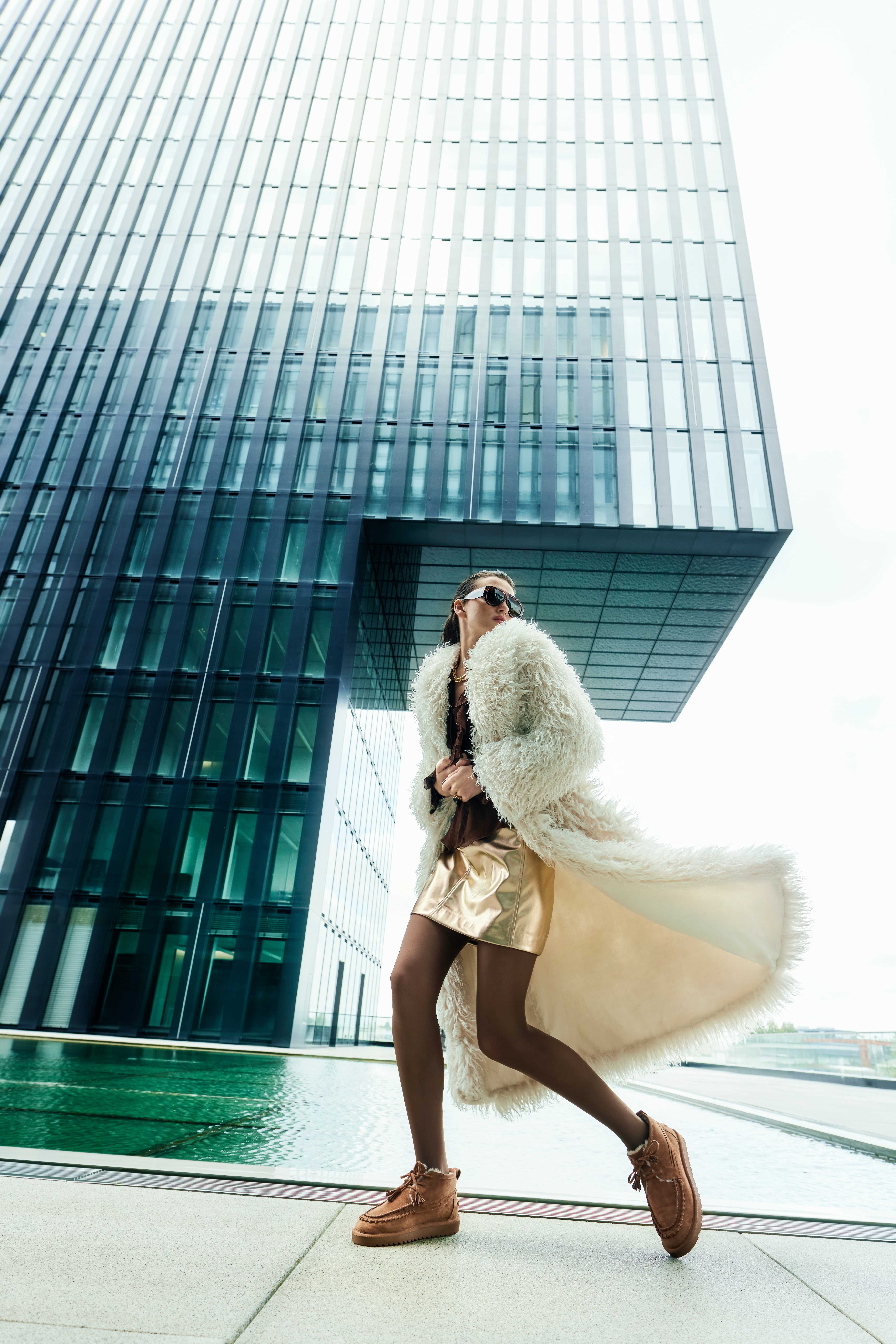 Frau in extravagantem Fashion-Look mit Fellmantel, Ledershorts und Boots