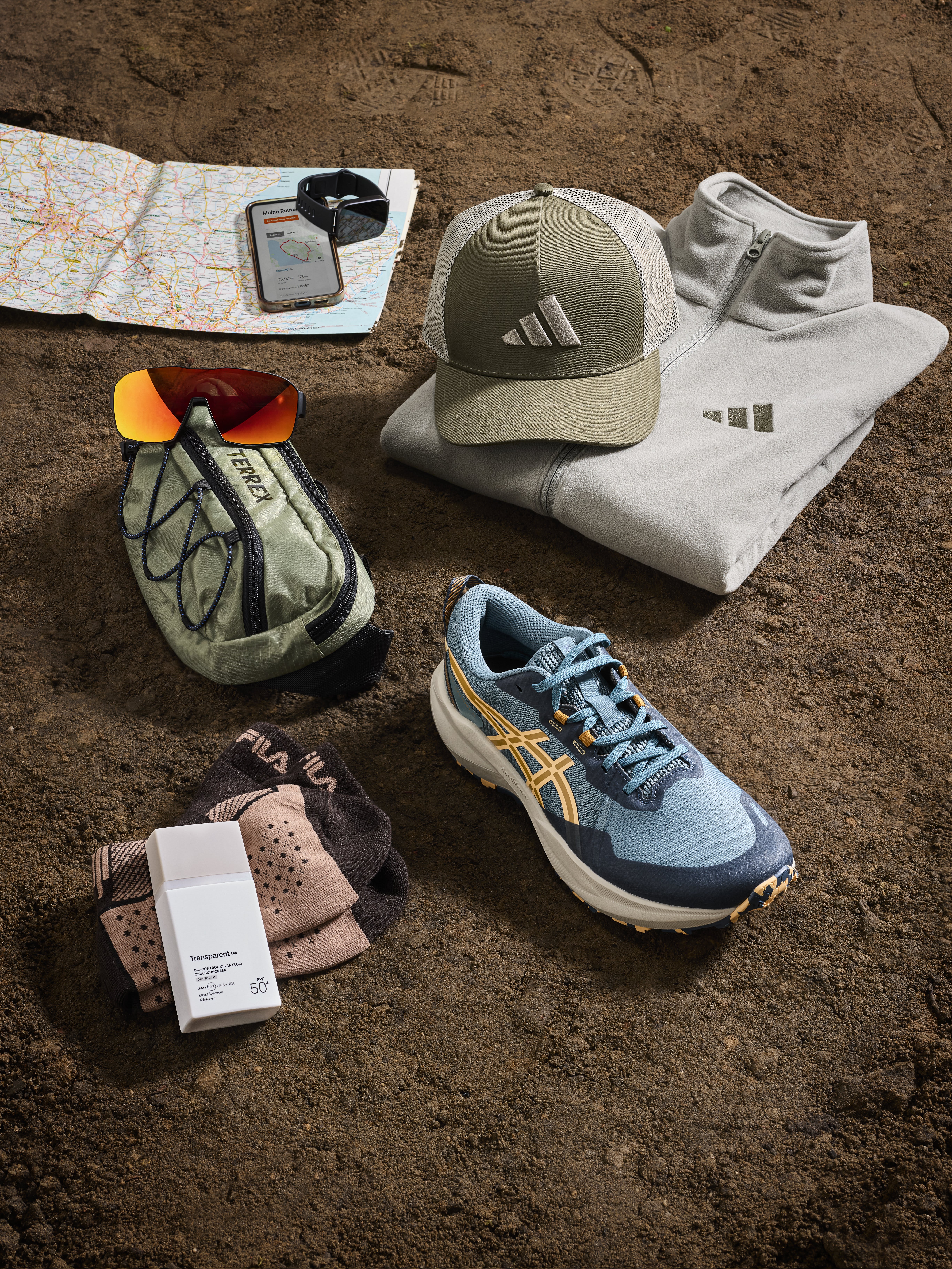 Trailrunning Utensilien wie eine Karte, eine Cap, eine grüne Bauchtasche, Socken und blaue Sportschuhe
