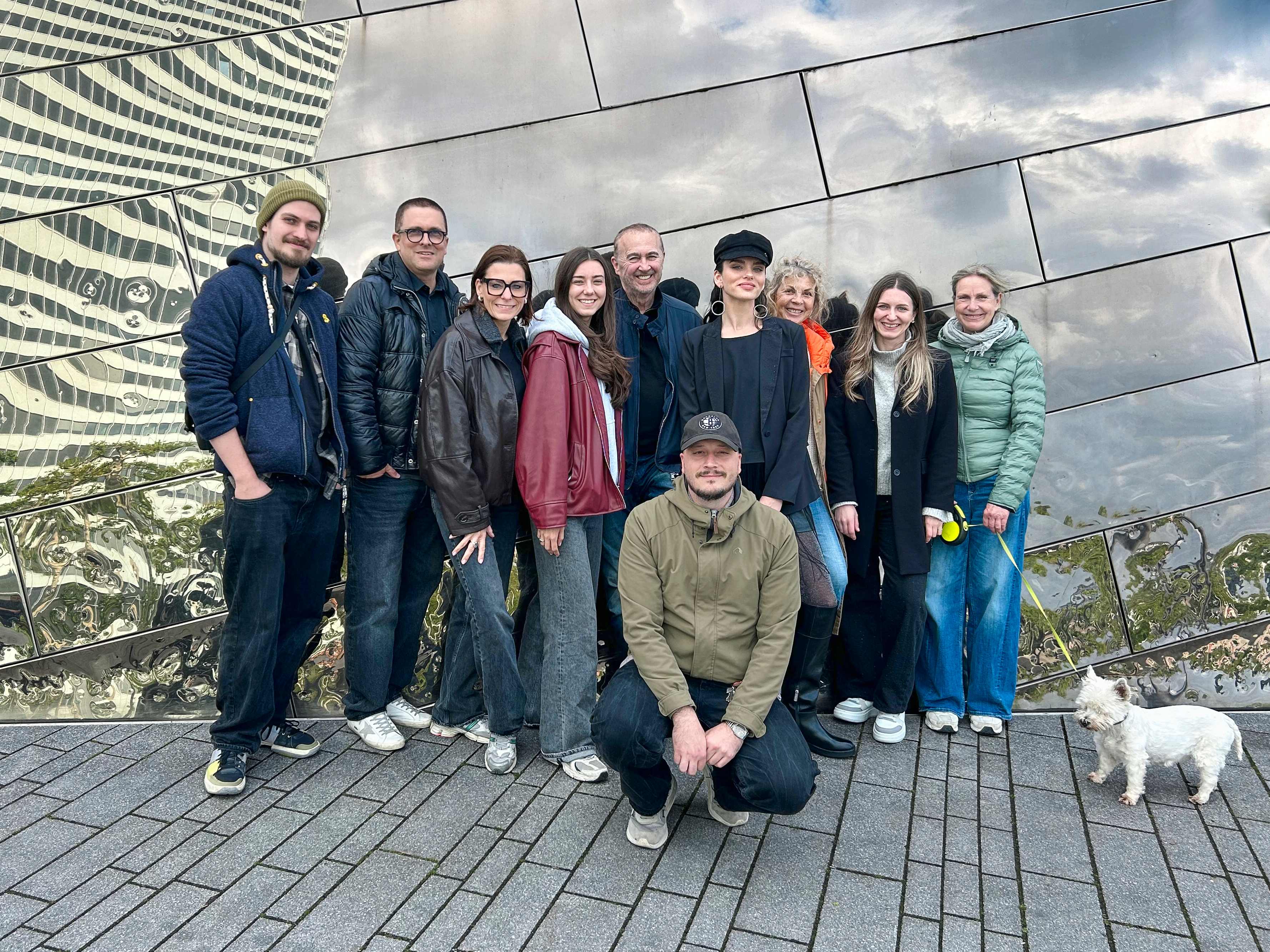 Gruppenfoto mit zehn Personen vor einer spiegelnden Gebäudefassade