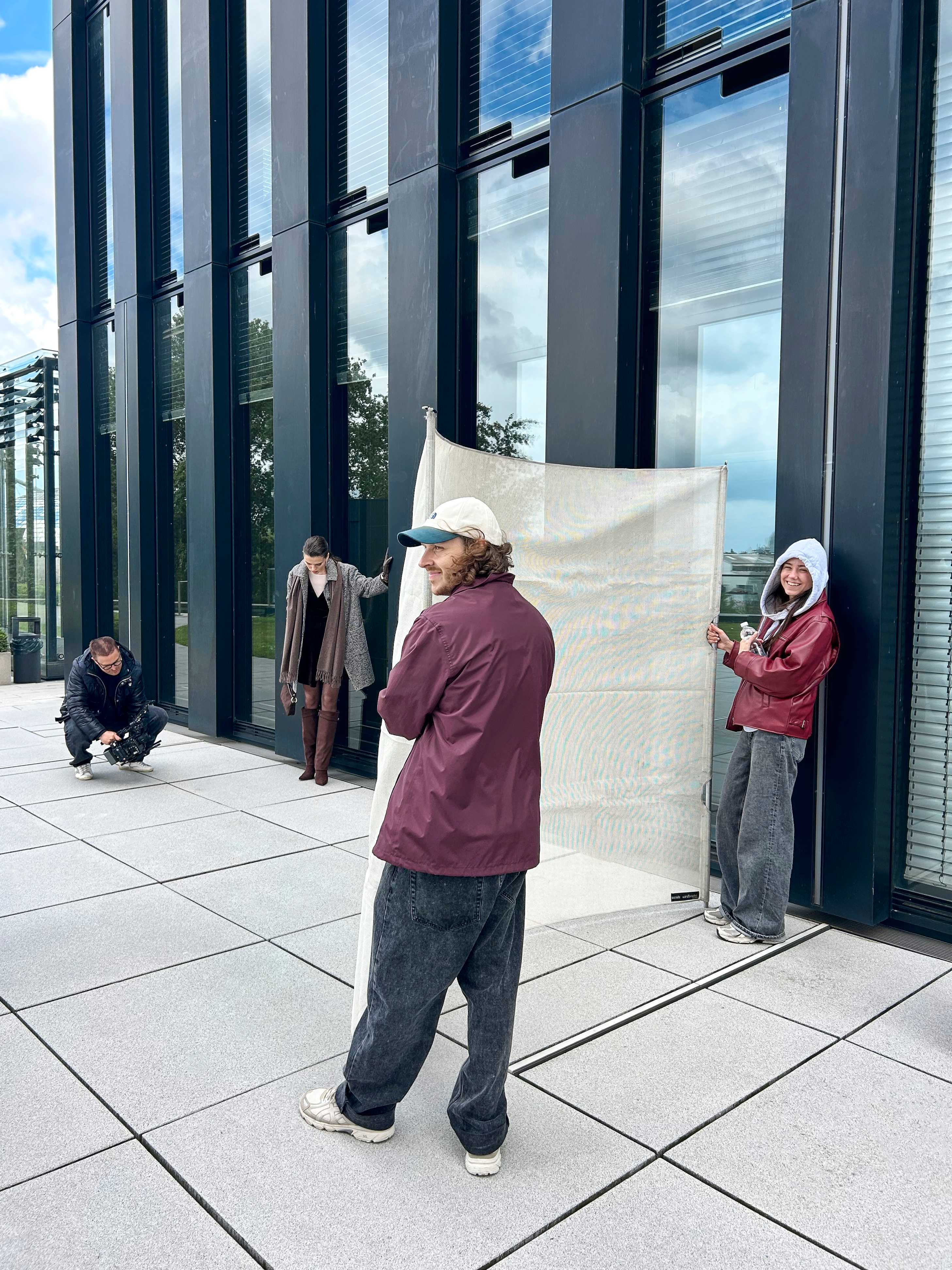Ein Fotograf filmt das Model, während zwei Personen einen Reflektor halten und die Szene ausleuchten