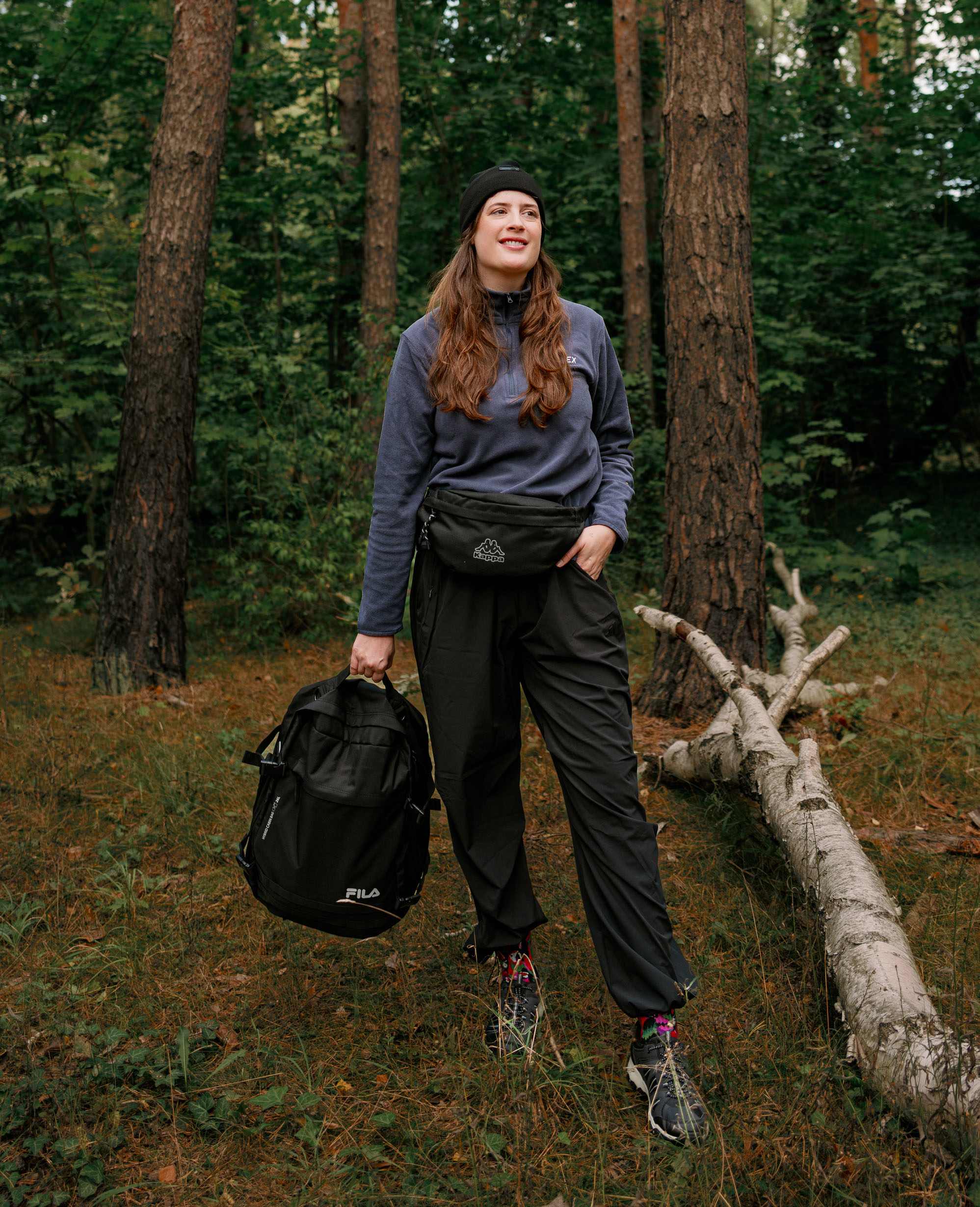 Frau im Wald mit Fleece Pullover, Mütze und Rucksack