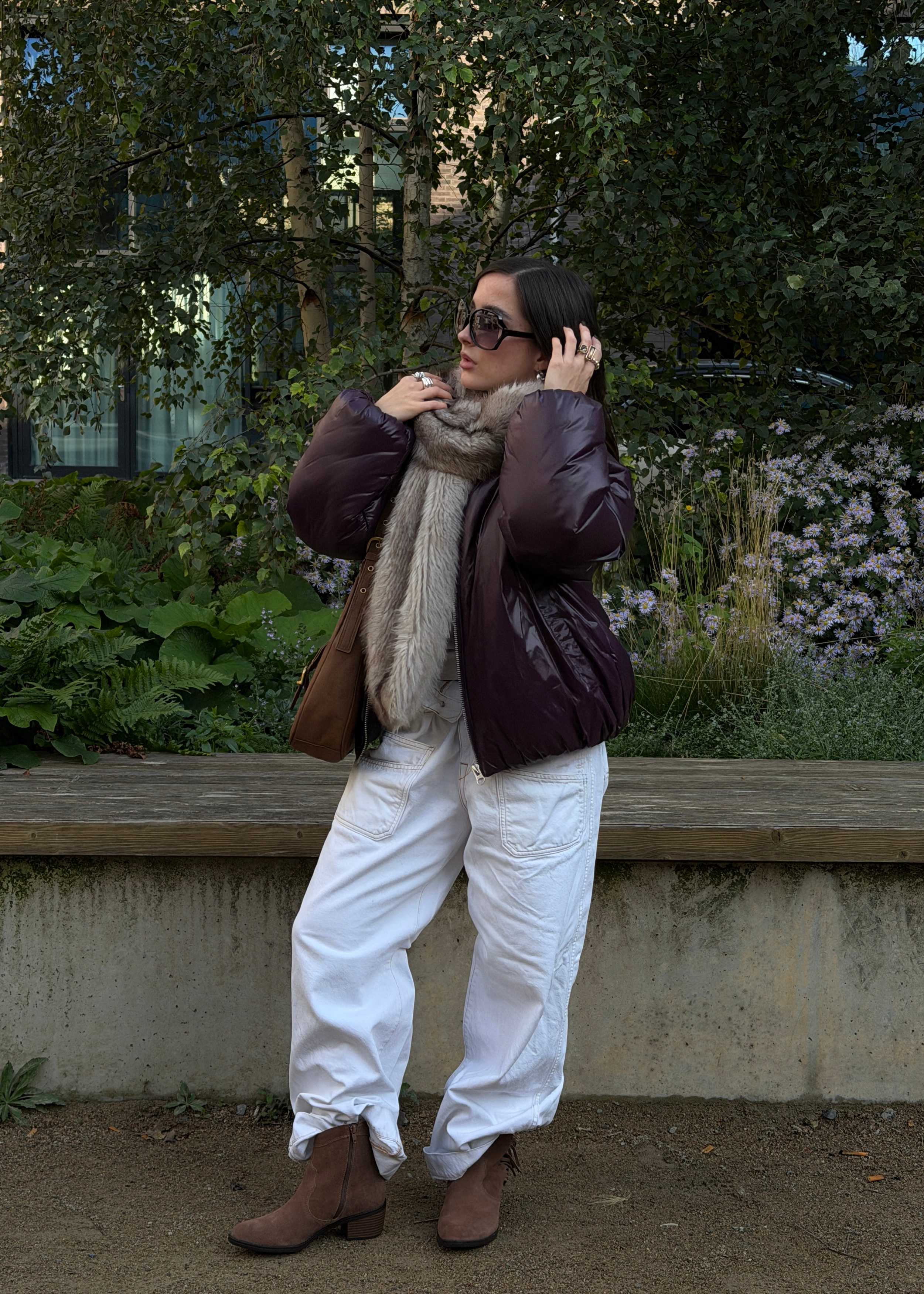 Frau in Park, trägt Denim-Hos mit Steppjacke