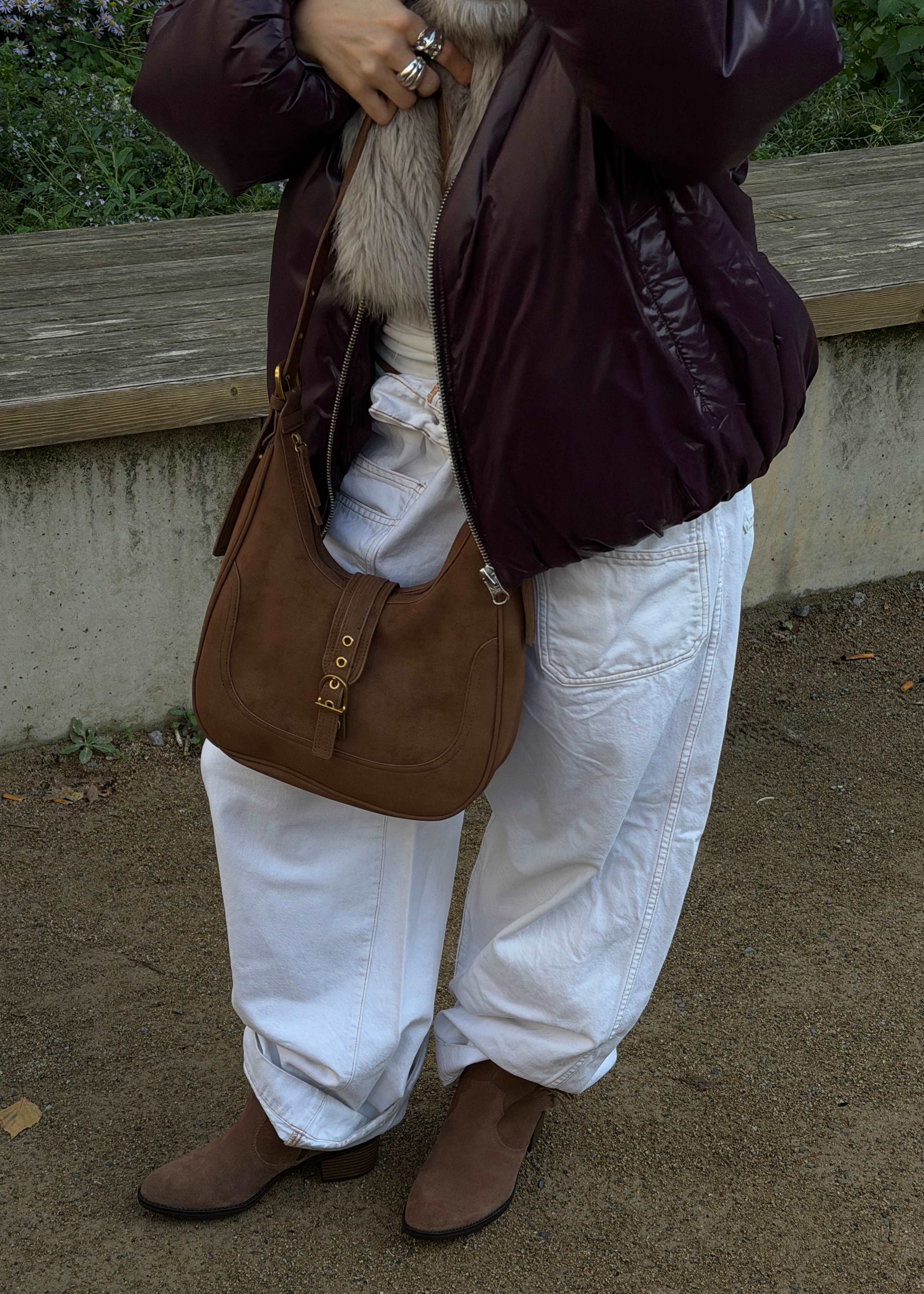 Frau mit weißer Baggy-Jeans, brauner Wildleder-Hobo-Bag und Westernstiefeletten aus Veloursleder