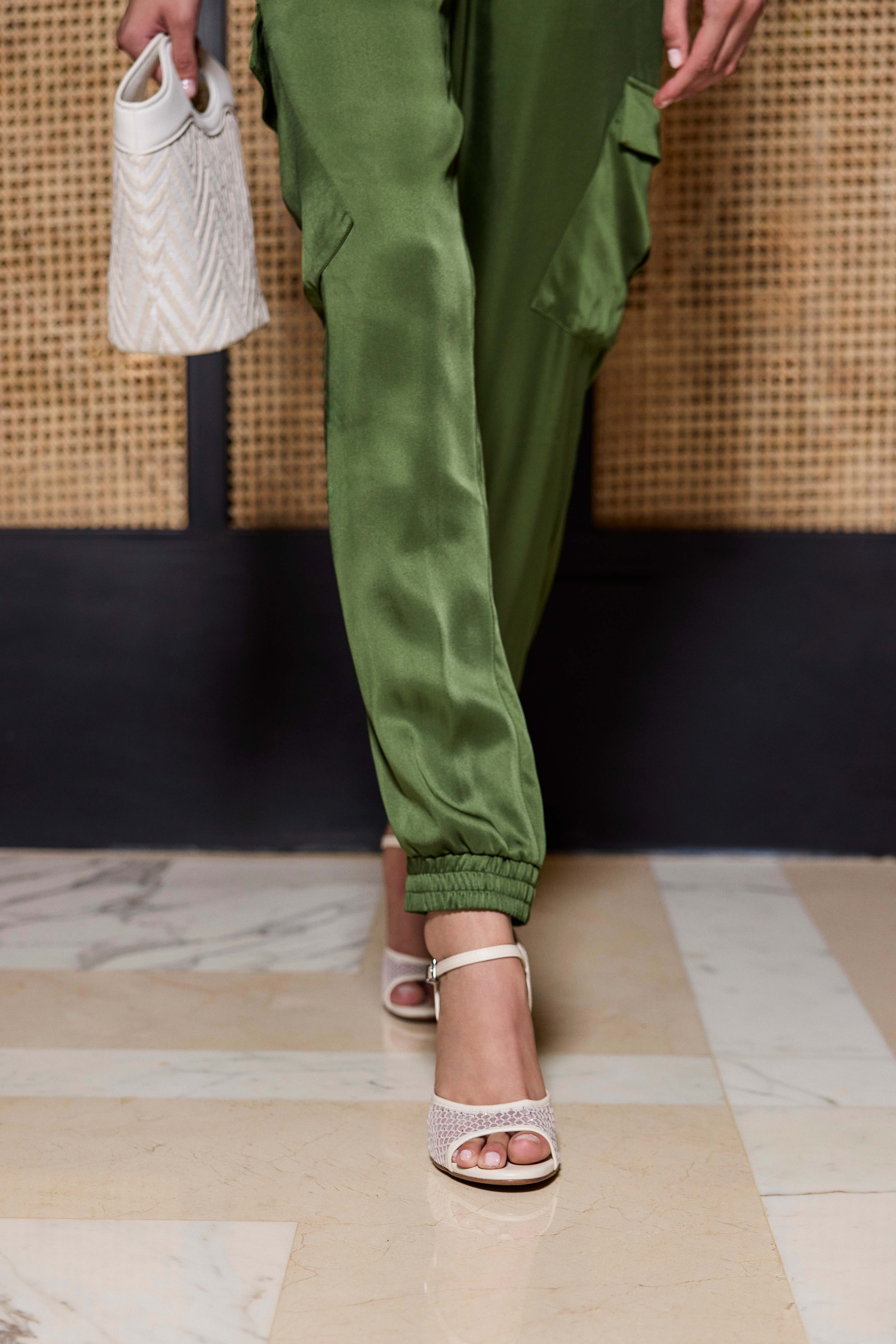 Nahaufnahme einer Frau mit samtig-grüner Hose und eleganten weißen Mesh-Schuhen