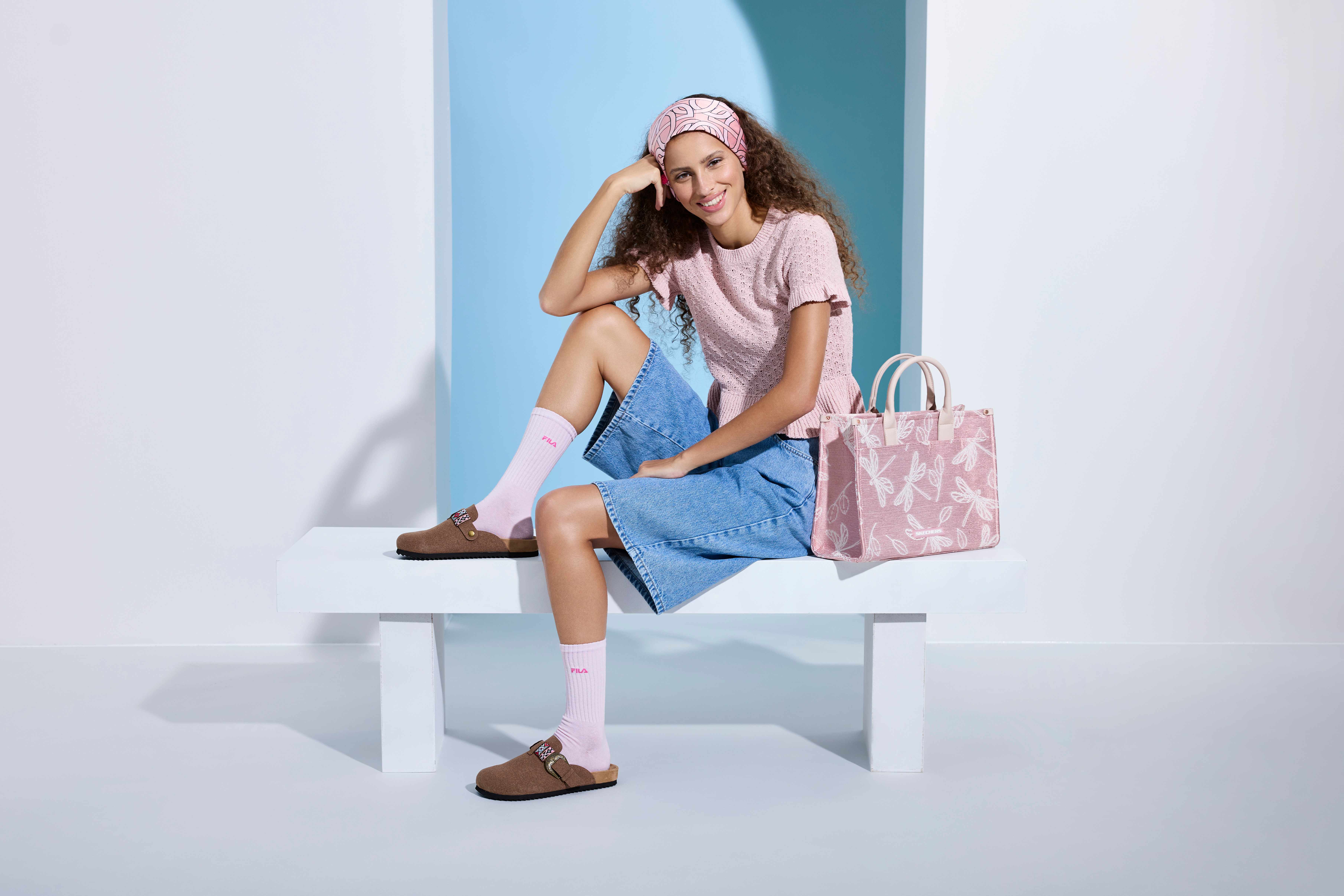 Frau in rosa Top und blauer Jeans-Shorts, sitzt auf kompakter weißer Sitzbank