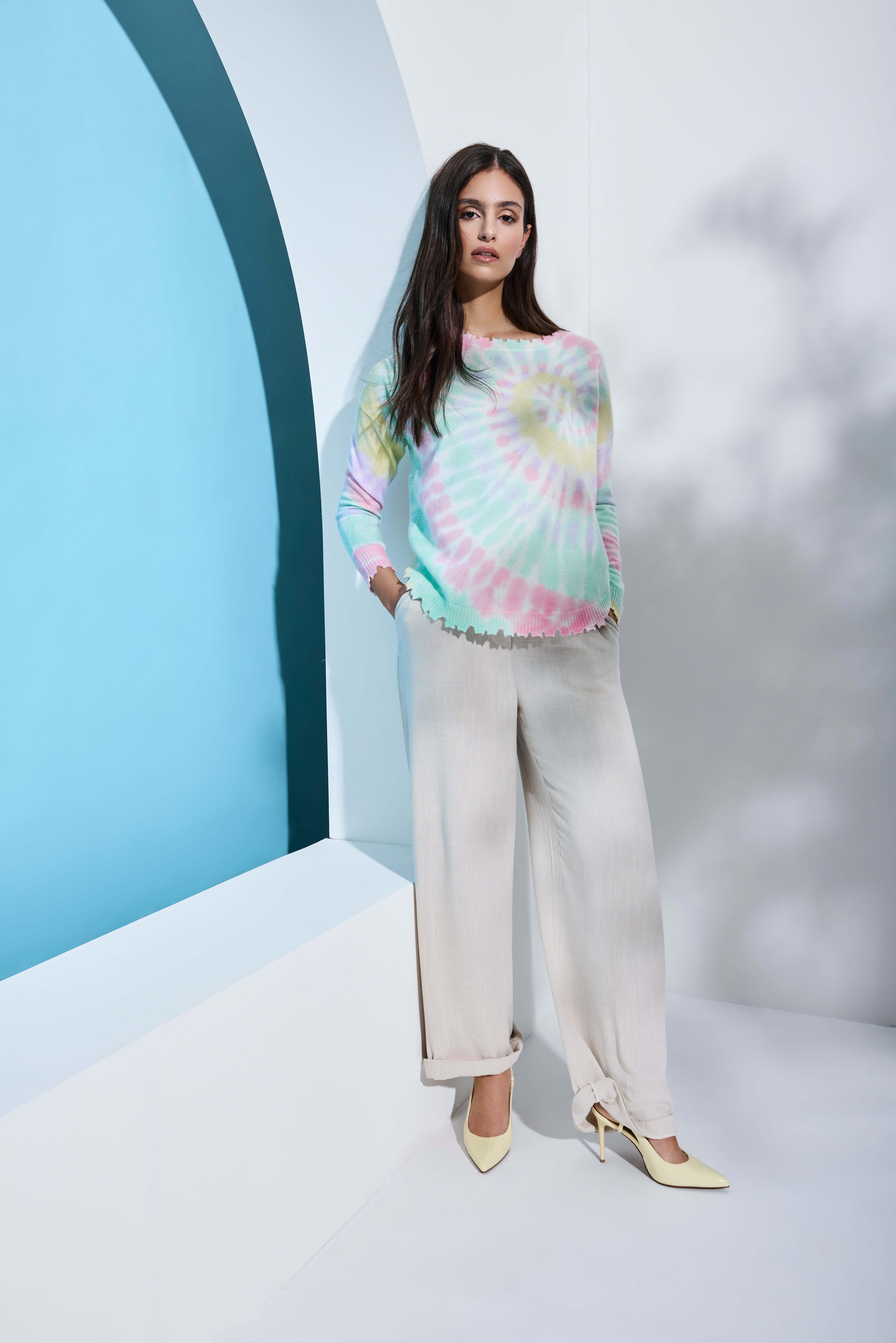 Frau trägt bunten Tie-Dye-Pullover, kombiniert mit Wide-Leg-Hose für den Casual Chic