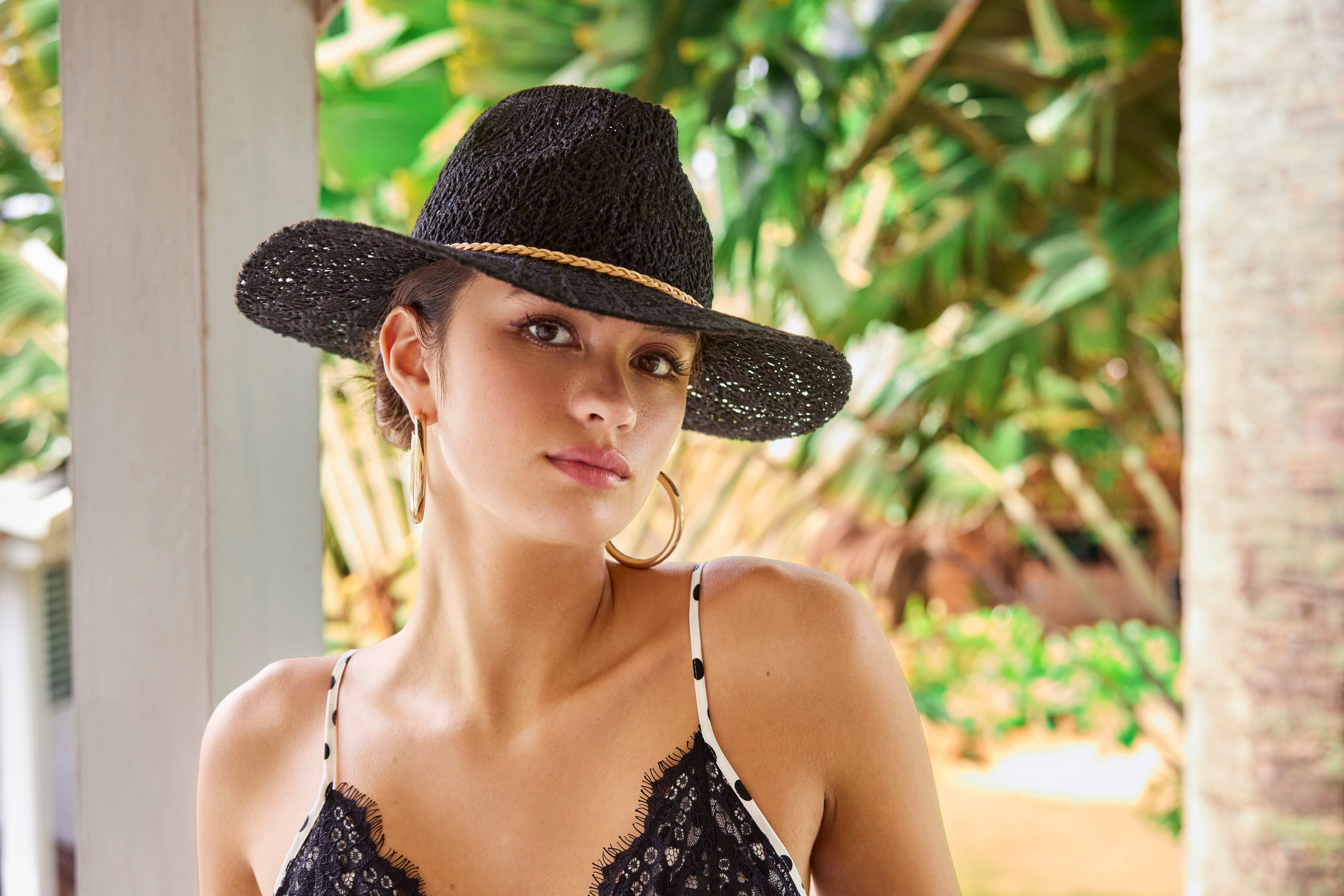 Frau in scwarzem Bikini-Top trägt passenden Sommerhut mit breiter Krempe 