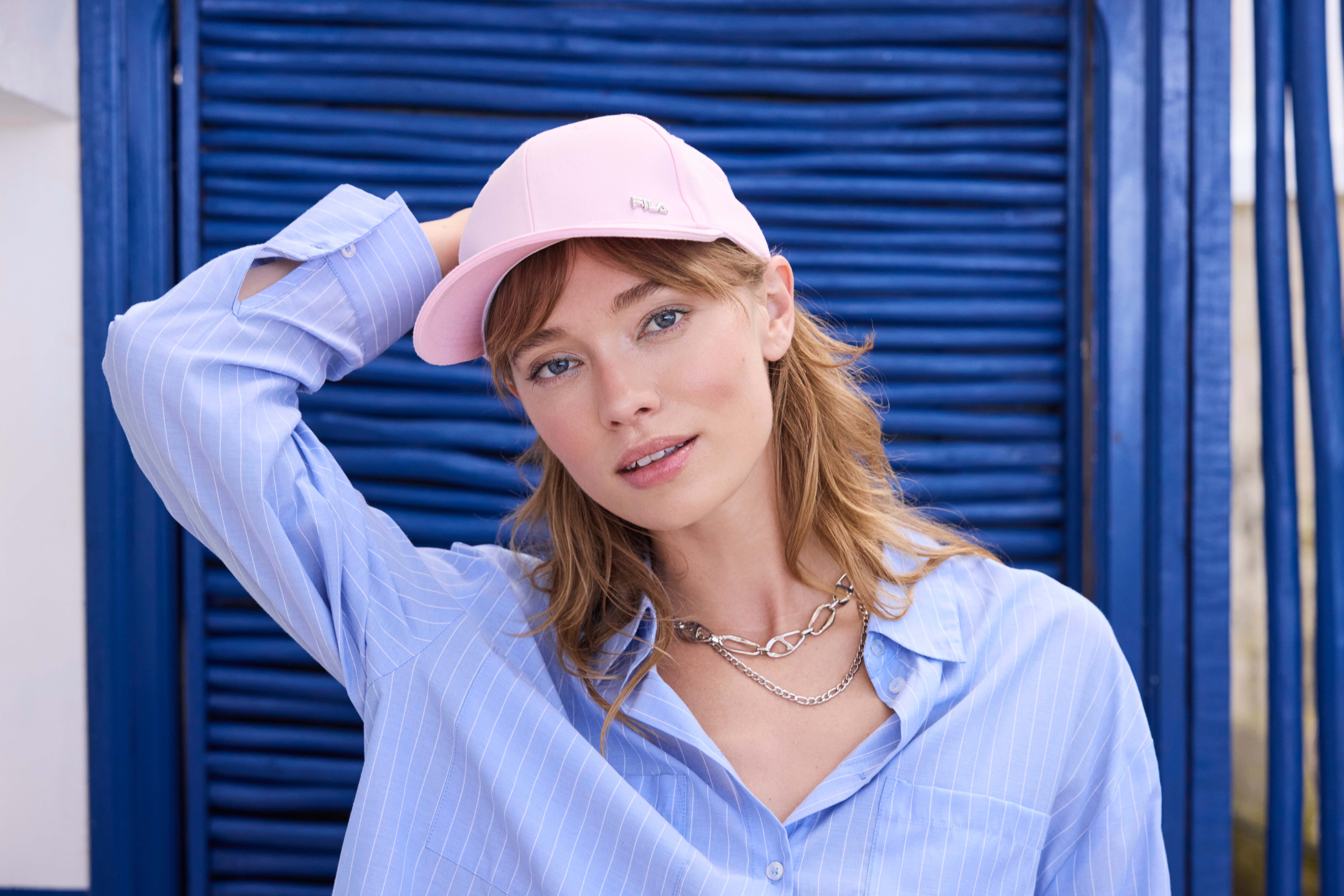 Blonde Frau in blauer Bluse mit rosa Cap auf dem Kopf