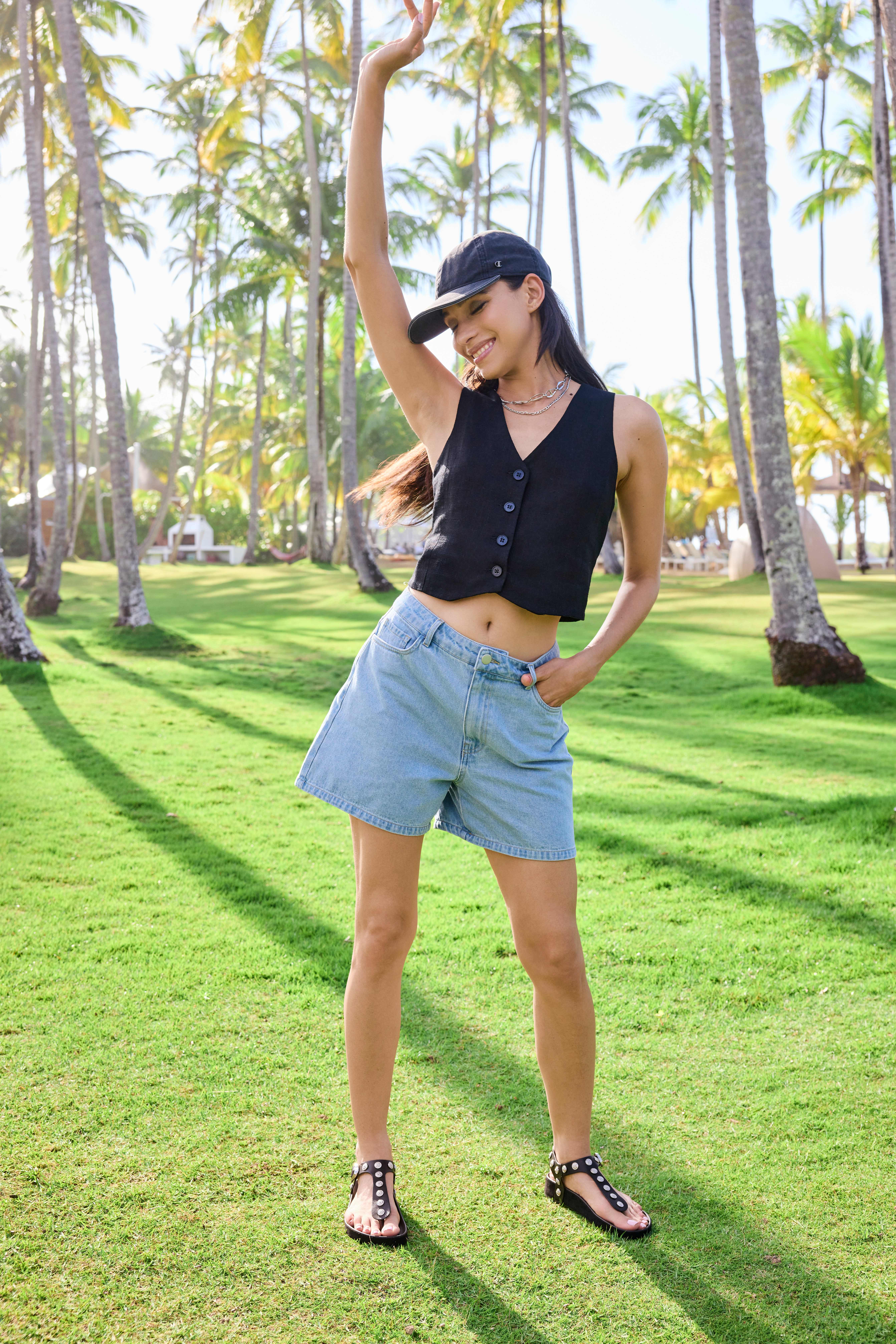 Frau mit Basecap, trägt schwarze Sommer-Weste und kurze Jeanshose