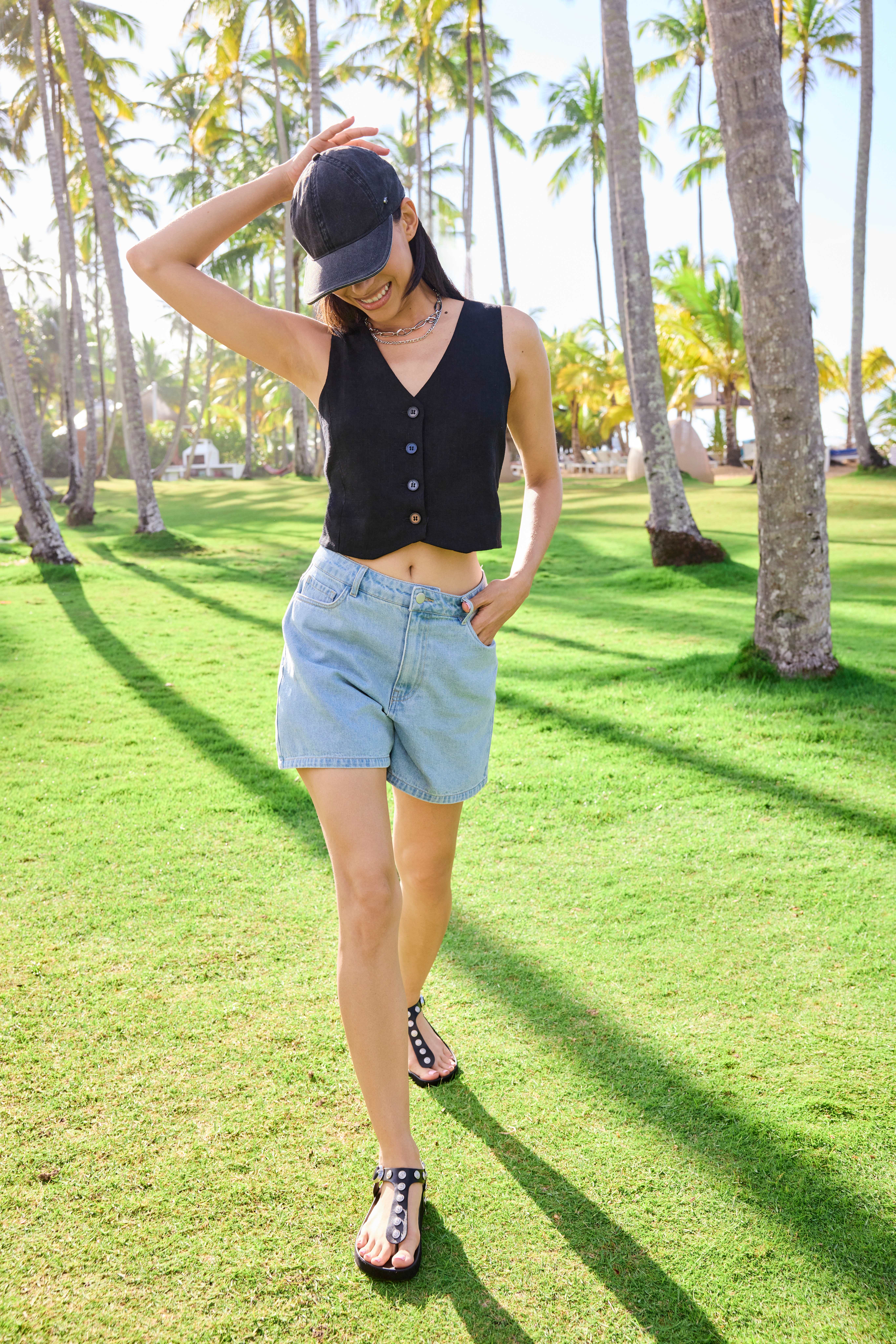 Frau spaziert auf Wiese, trägt schwarzes Baumwoll-Top zu heller Denim-Shorts