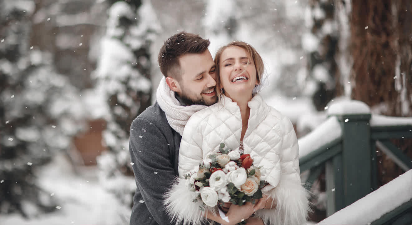 Mann und Frau lachend in winterlicher Kulisse