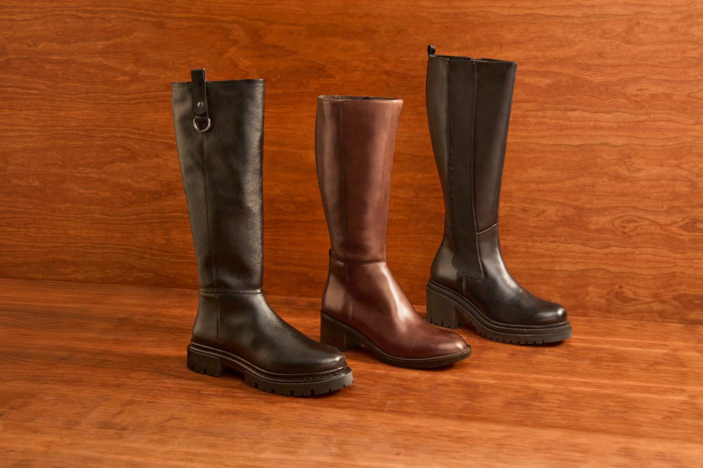Drei Stiefel mit hohem Schaft aus Leder stehen nebeneinander am Boden