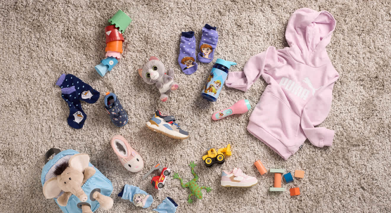 Kollektion einzelner Kinder-Kleidungsstücke & Accessoires auf einem Teppich