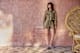 Frau in Leoprint-Outfit, mit Bluse und Shorts, lehnt an Wand