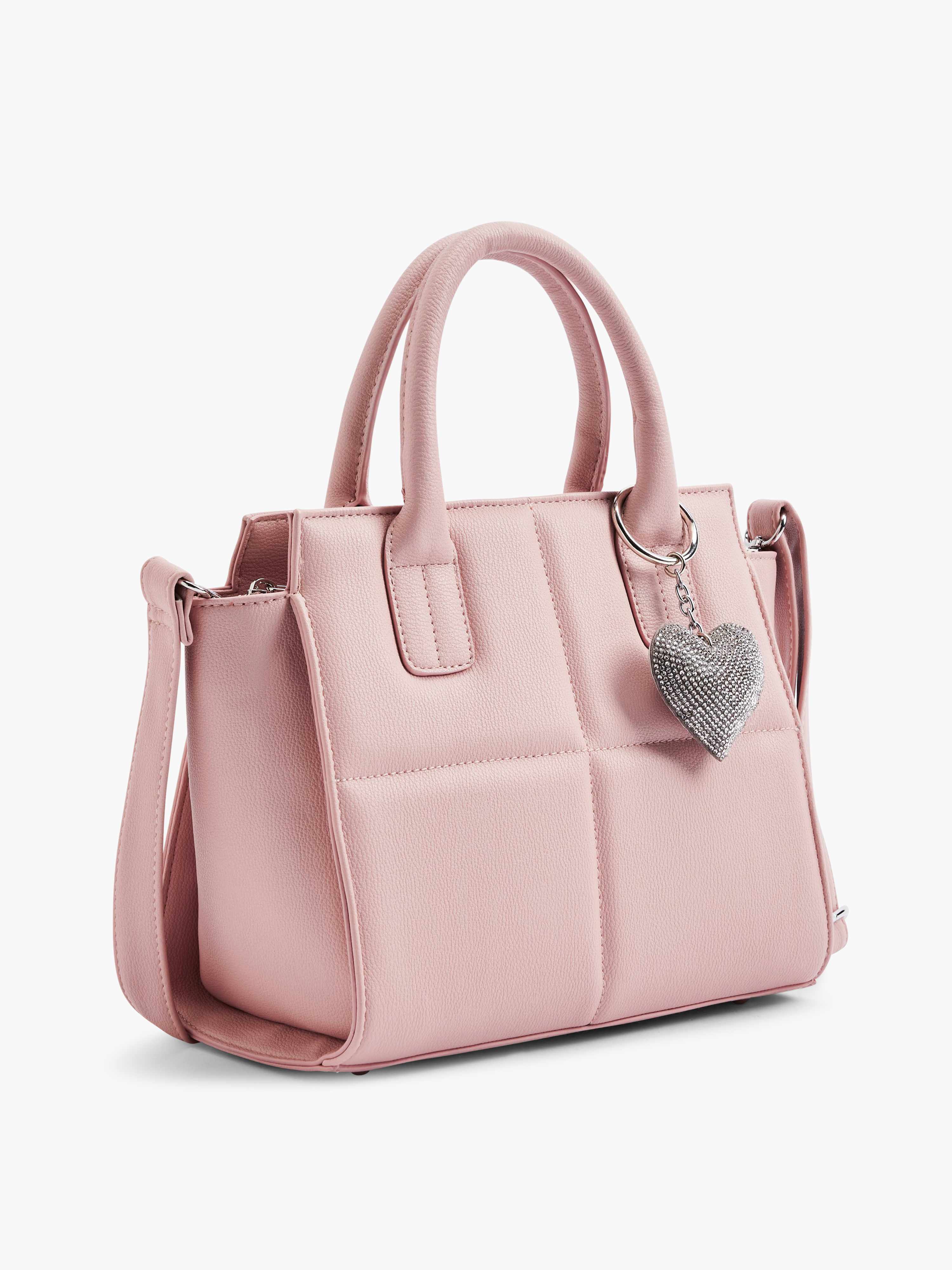 Rosafarbene Handtasche mit silbernem Herzanhänger, Steppoptik, vor weißem Hintergrund
