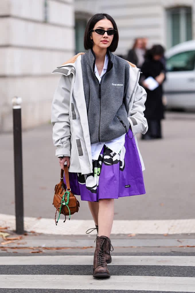 Frau mit Sonnenbrille trägt Layering-Kombination aus Jacke und Baumwoll-Weste bei einem Spaziergang