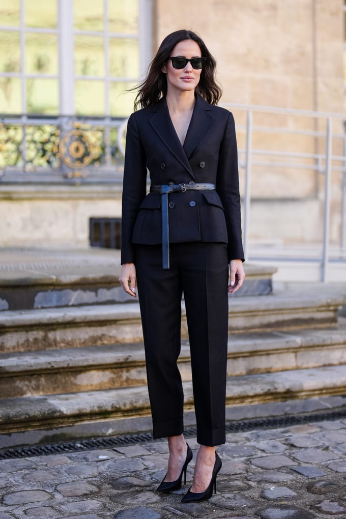 Frau mit Sonnenbrille und schwarzem Zweireiher, interpretiert als Kleid, kombiniert mit High Heels
