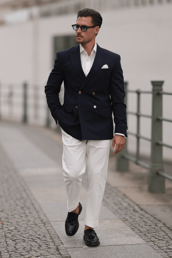 Mann in elegantem Zweireiher-Blazer in Schwarz, kombiniert mit weißer Hose für den formellen Look