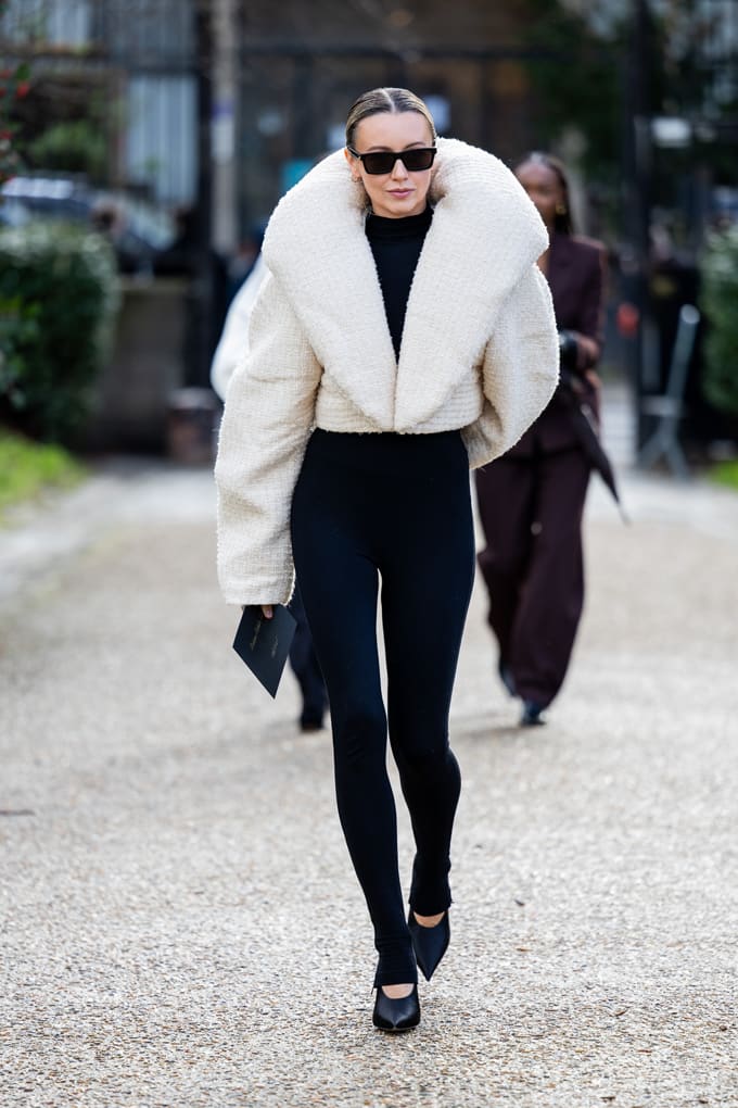 Frau in schicker Outfit-Kombination mit weißem Teddy-Oberteil und schwarzer Yogapants