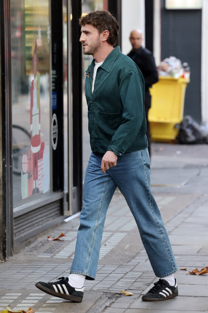 Paul Mescal, mit grünem Hoodie und Jeans, in urbaner Umgebung